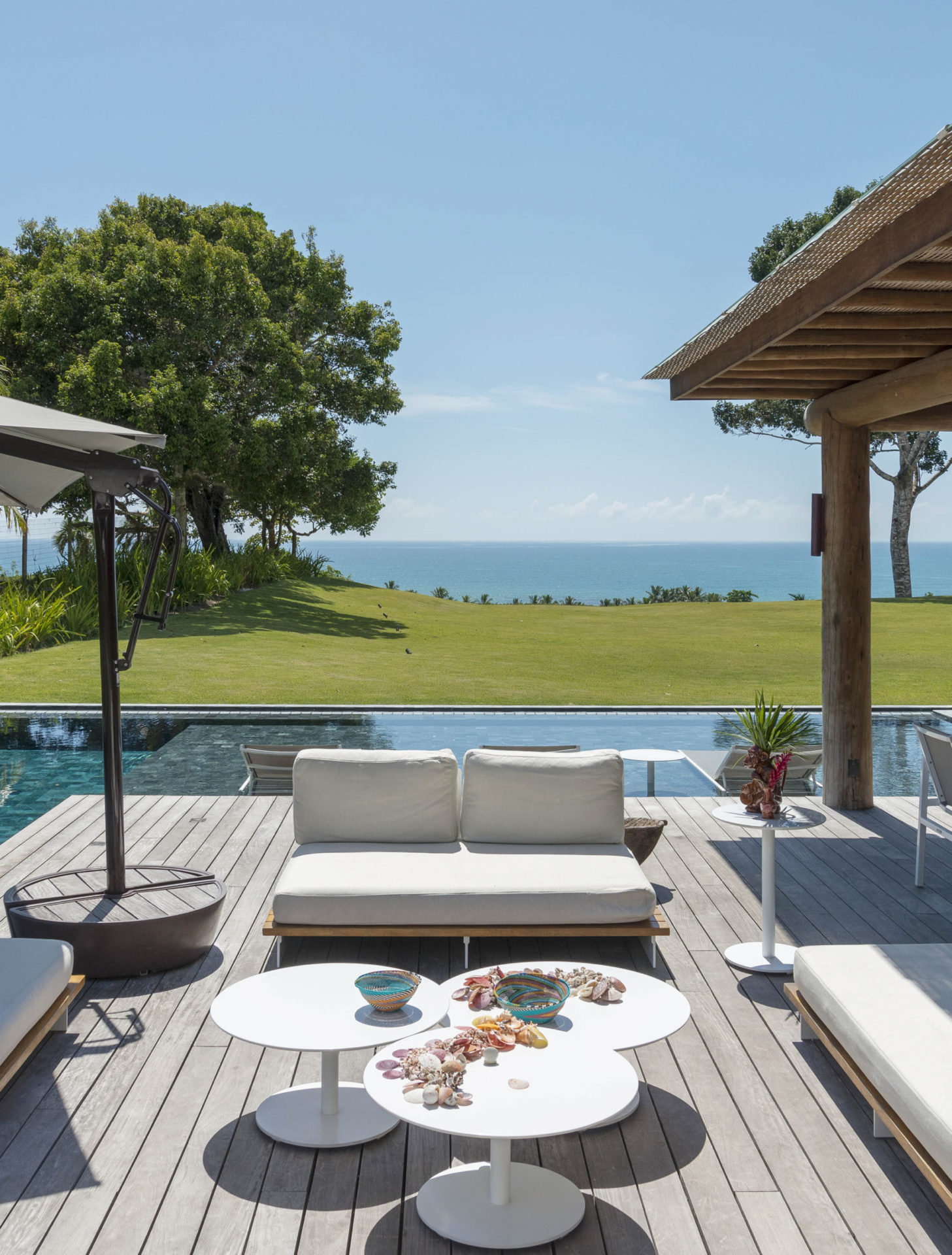 espaço de convivência à beira da piscina com sofás e mesinhas