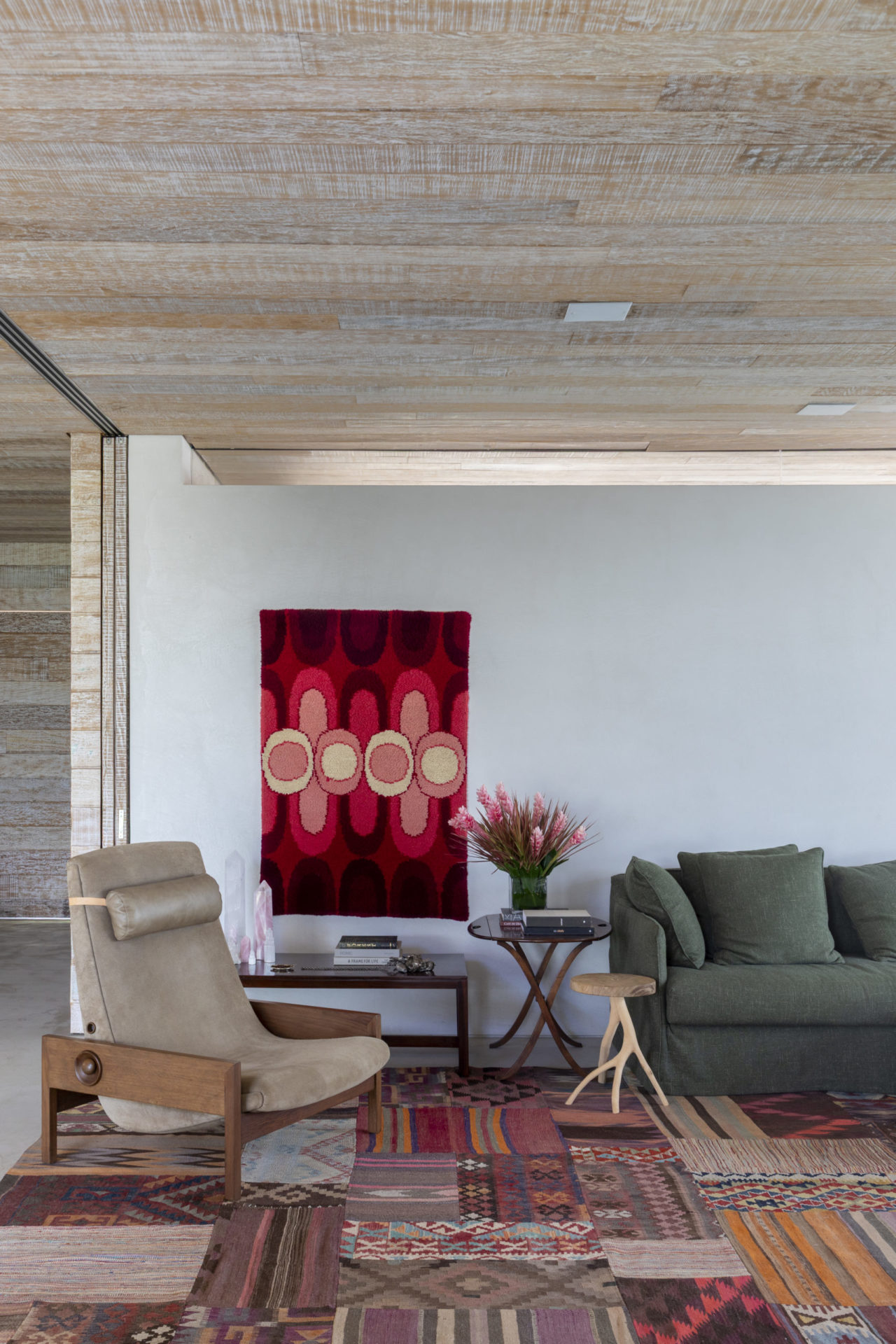 sala com poltrona, sofá, quadro nos tons de vermelho na parede e tapete