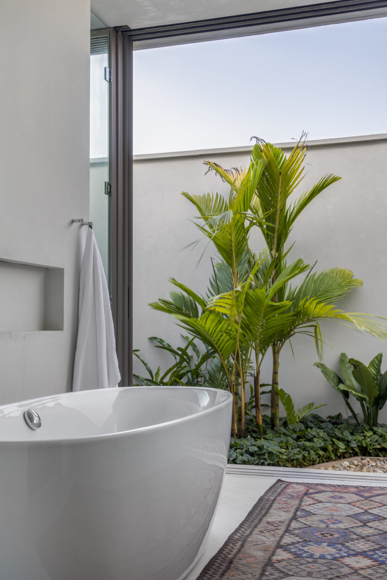 banheira branca, tolha branca pendurada e plantas