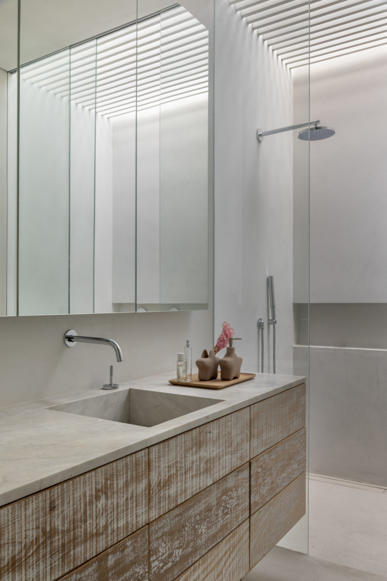 banheiro com bancada, espelho e chuveiro