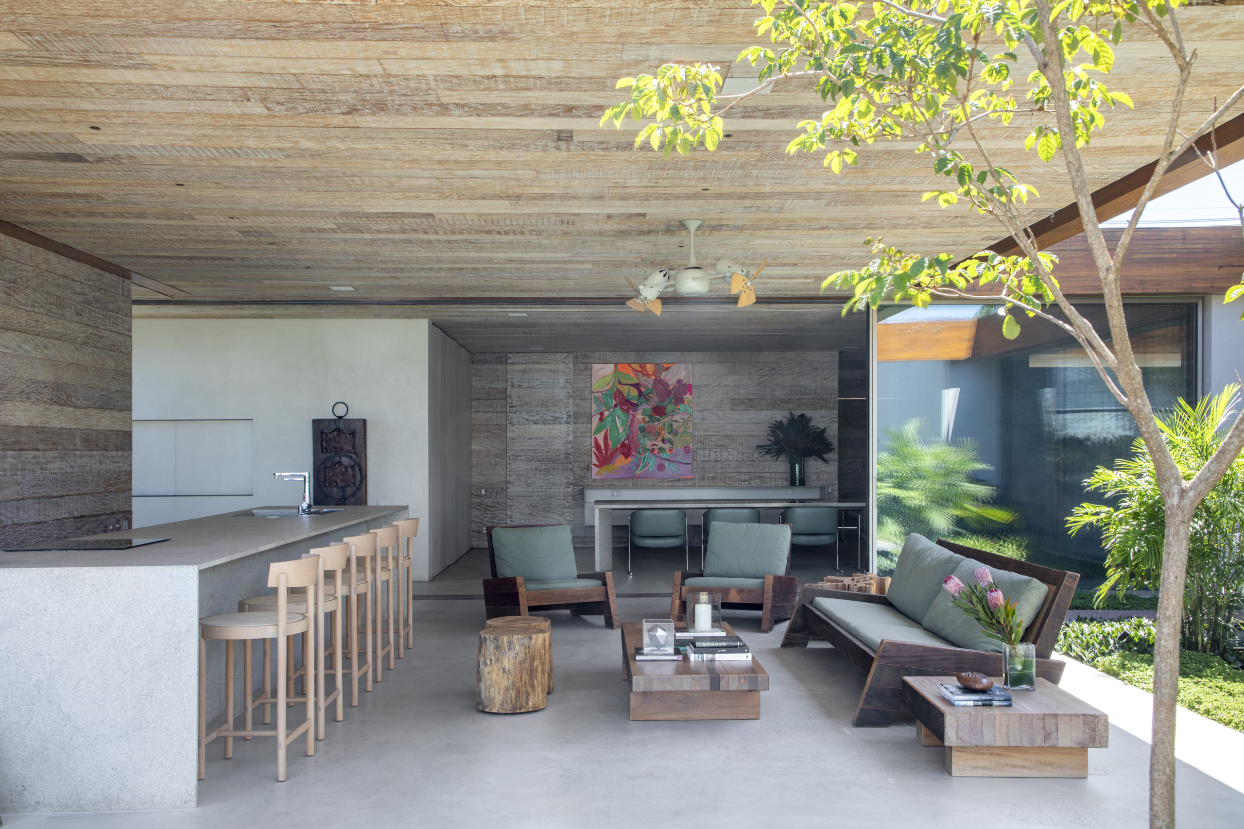 espaço com bancada, banquetas, sofá e mesa de centro