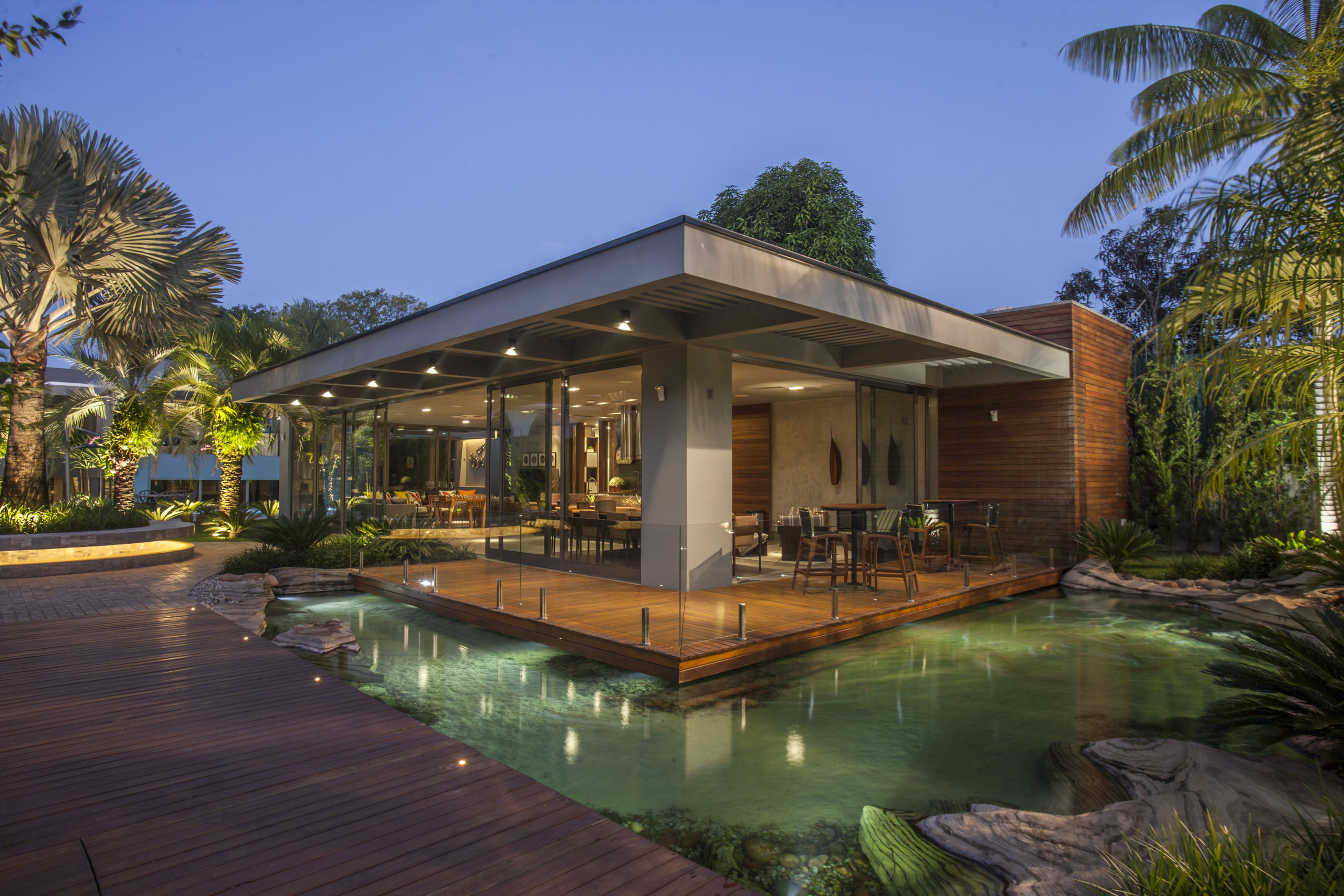 na foto uma casa iluminada e rodeada por um lago