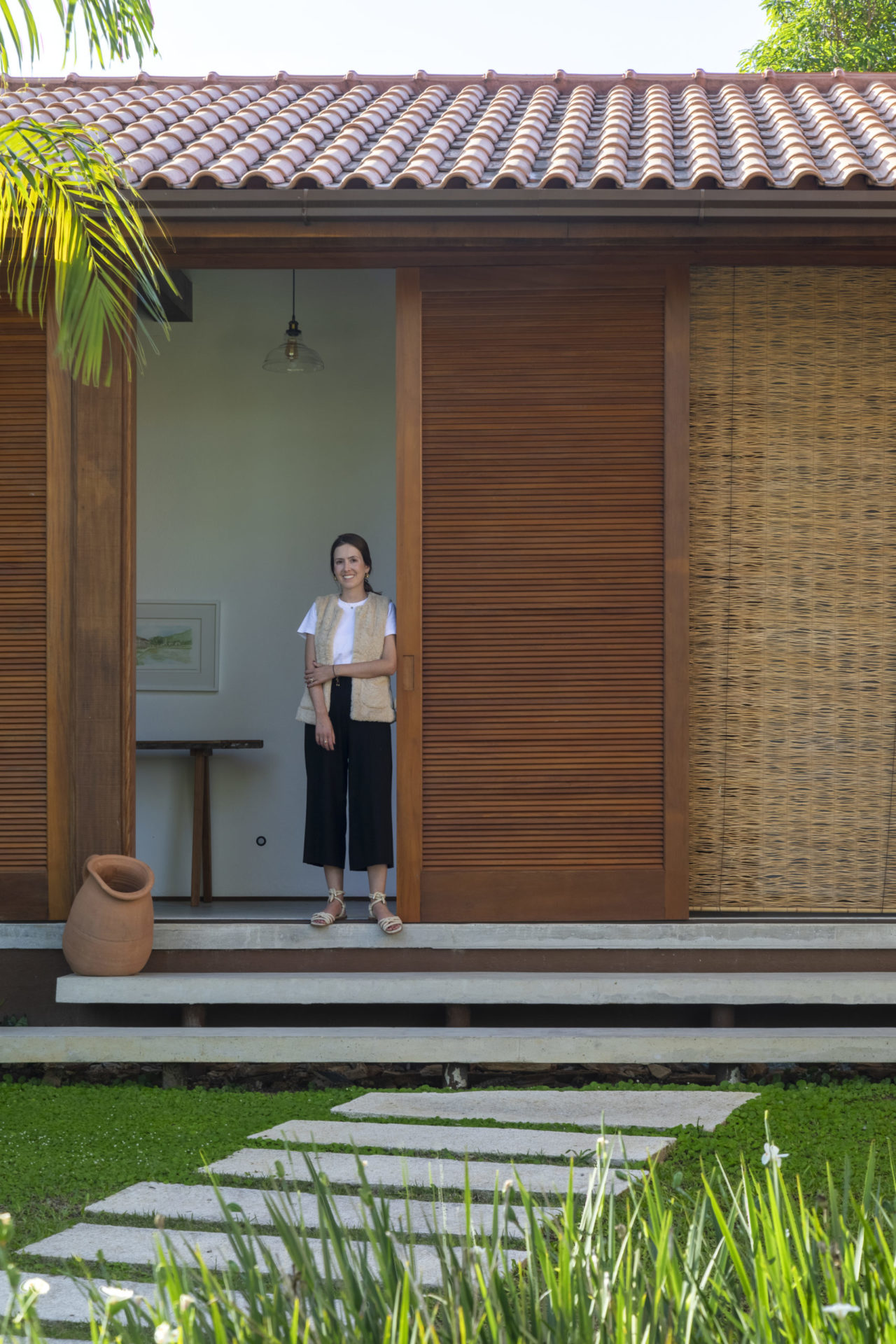 mulher branca e de cabelos castanhos na porta de um casa de campo