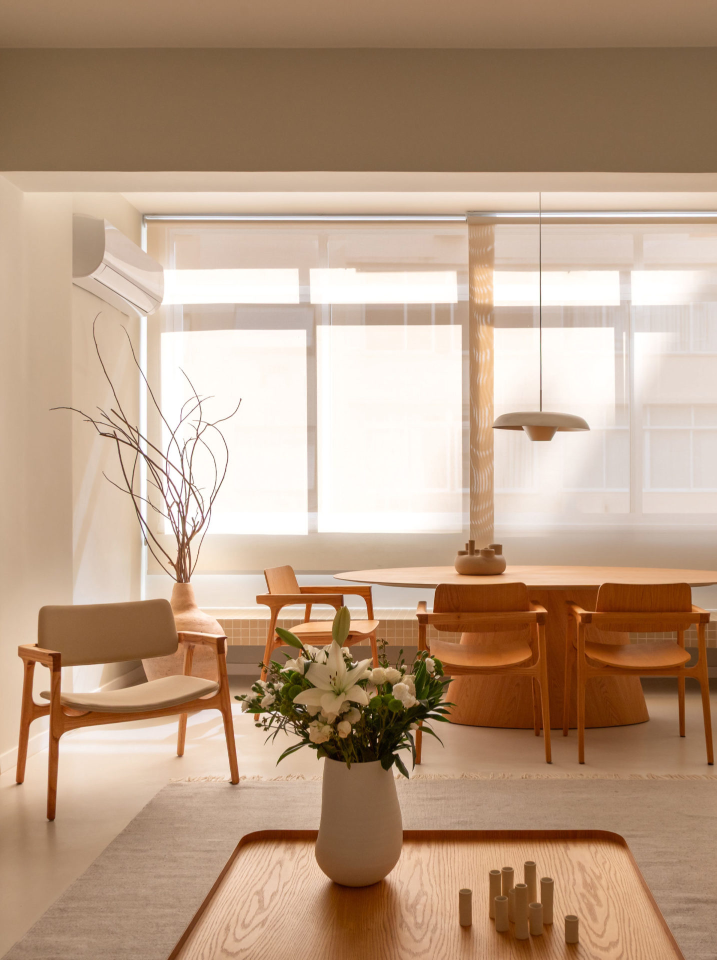 na foto sala com grande janela, cortina, mesa de madeira e uma cadeira