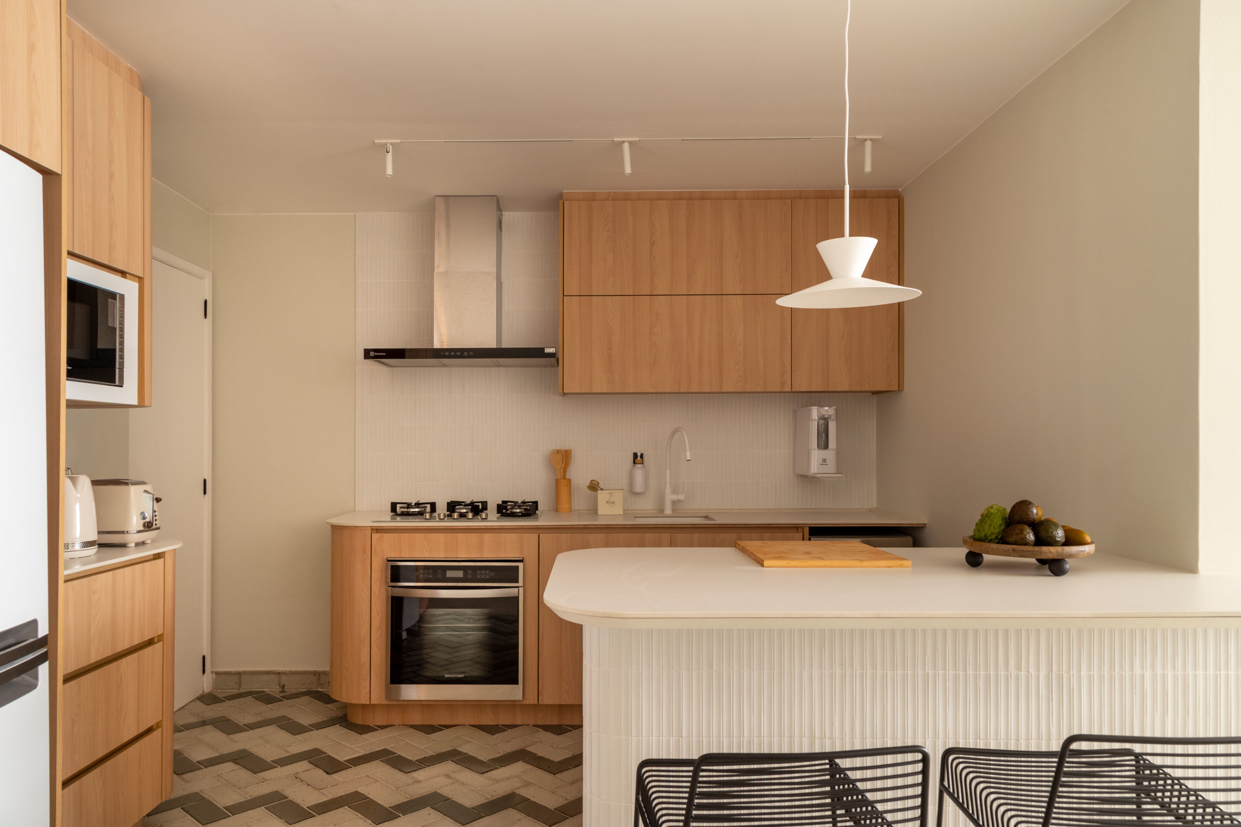 cozinha com bancada branca, piso em preto e branco e armários de madeira