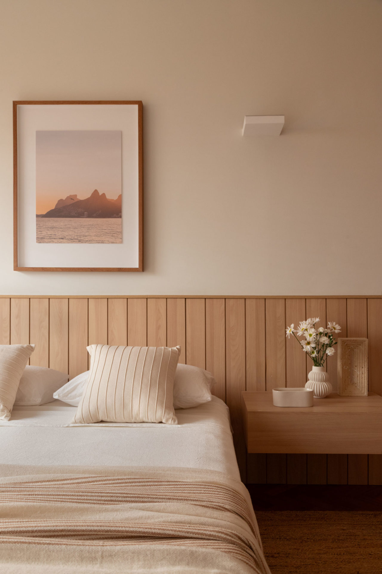 na foto cama com almofadas brancas e mesinha de cabeceira