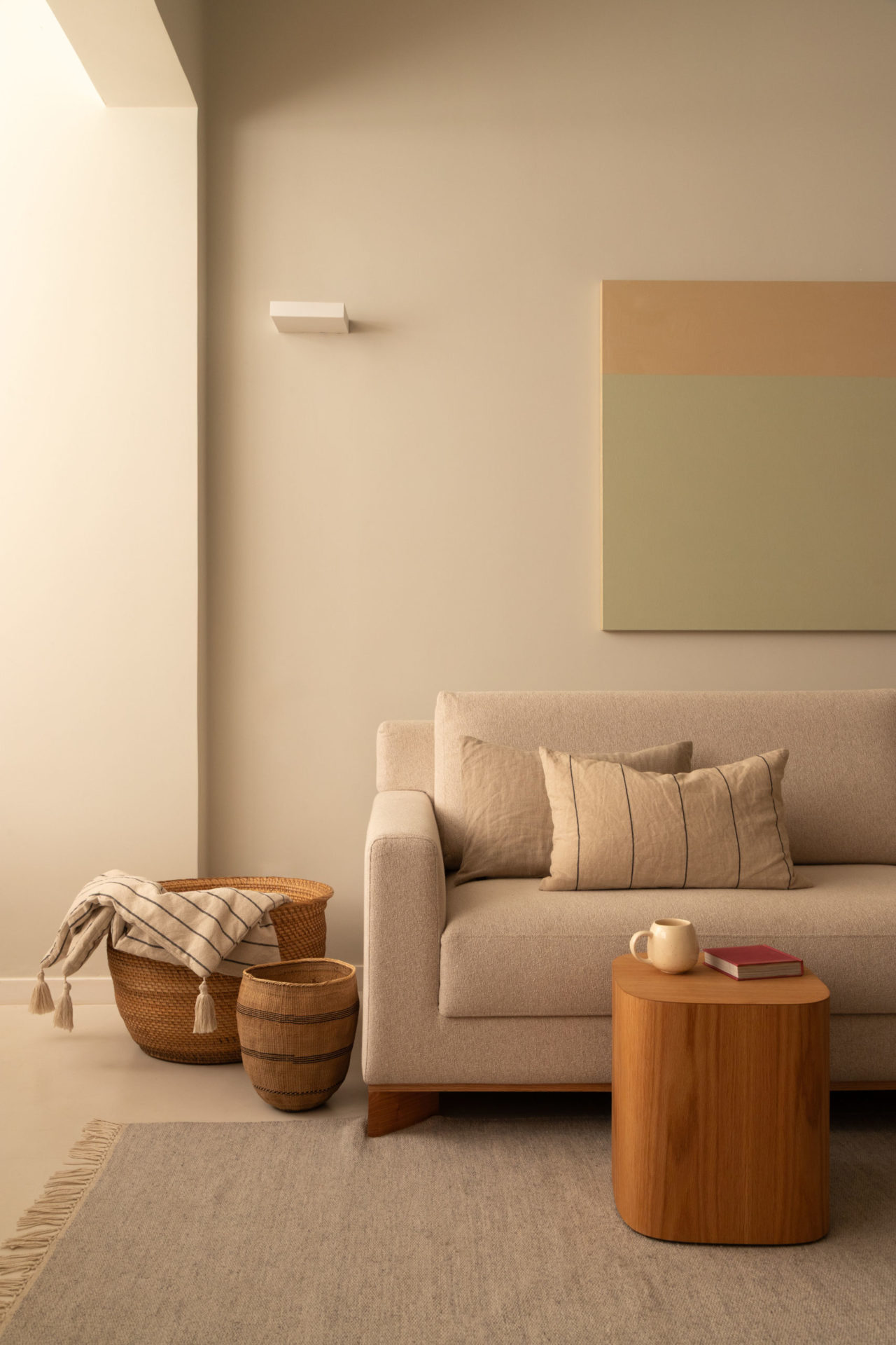 na foto sofá branco com almofadas no mesmo tom, quadro em tons pastéis na parede 