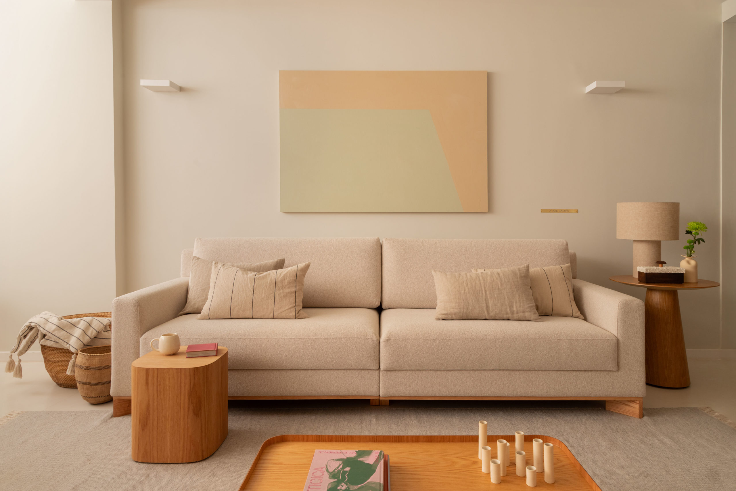 na foto sofá em off-white, mesa de centro de madeira clara e quadro na parede