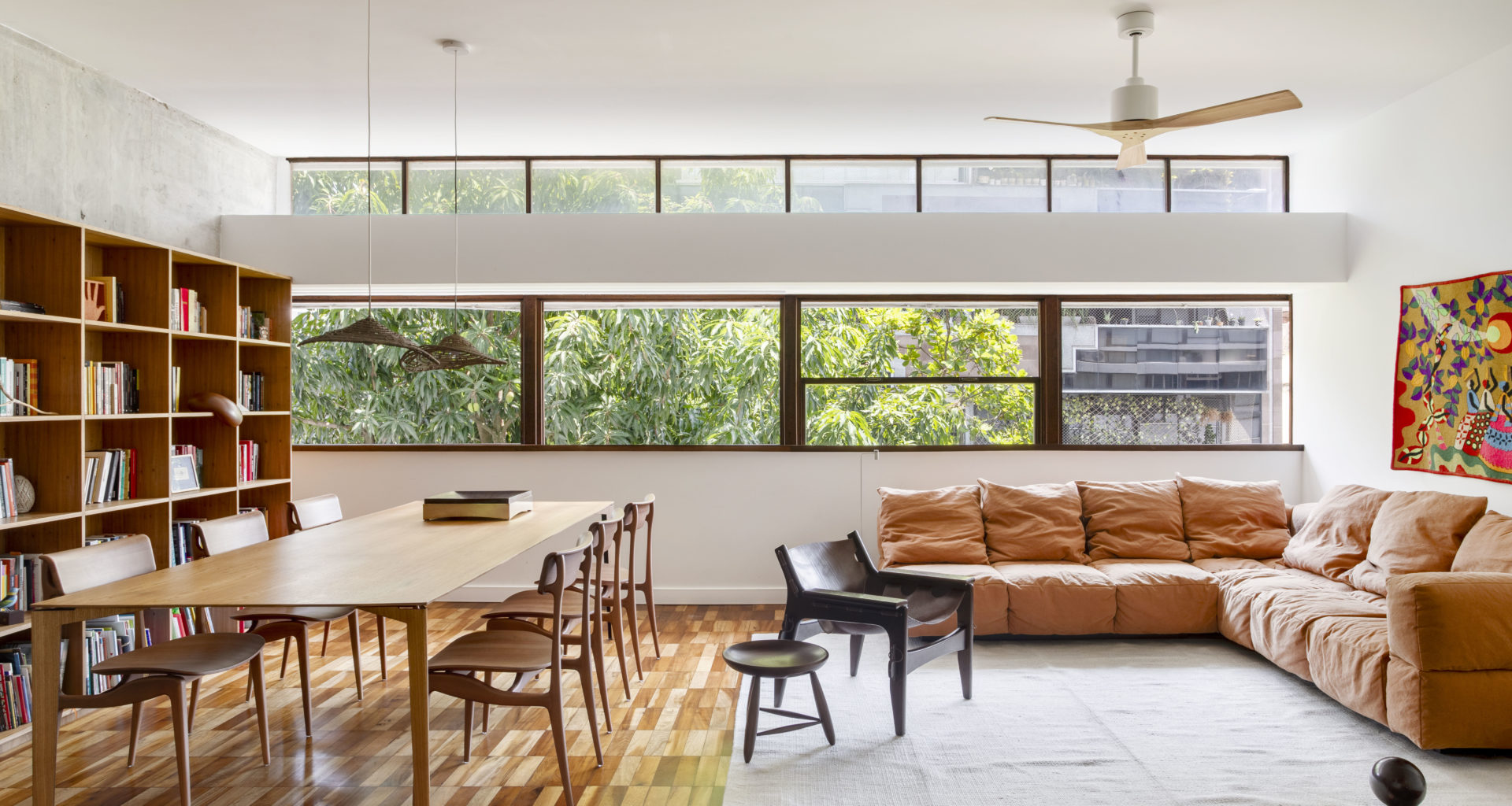 na foto uma sala de janela grande, mesa de jantar, sofá, poltrona