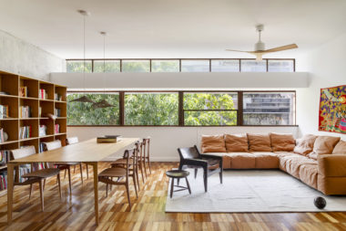 na foto uma sala de janela grande, mesa de jantar, sofá, poltrona