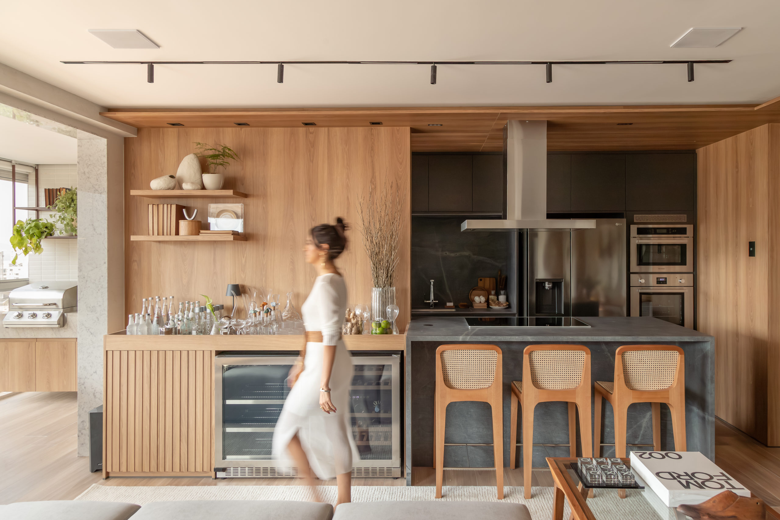 na foto uma cozinha e um bar e um mulher branca de cabelo preso