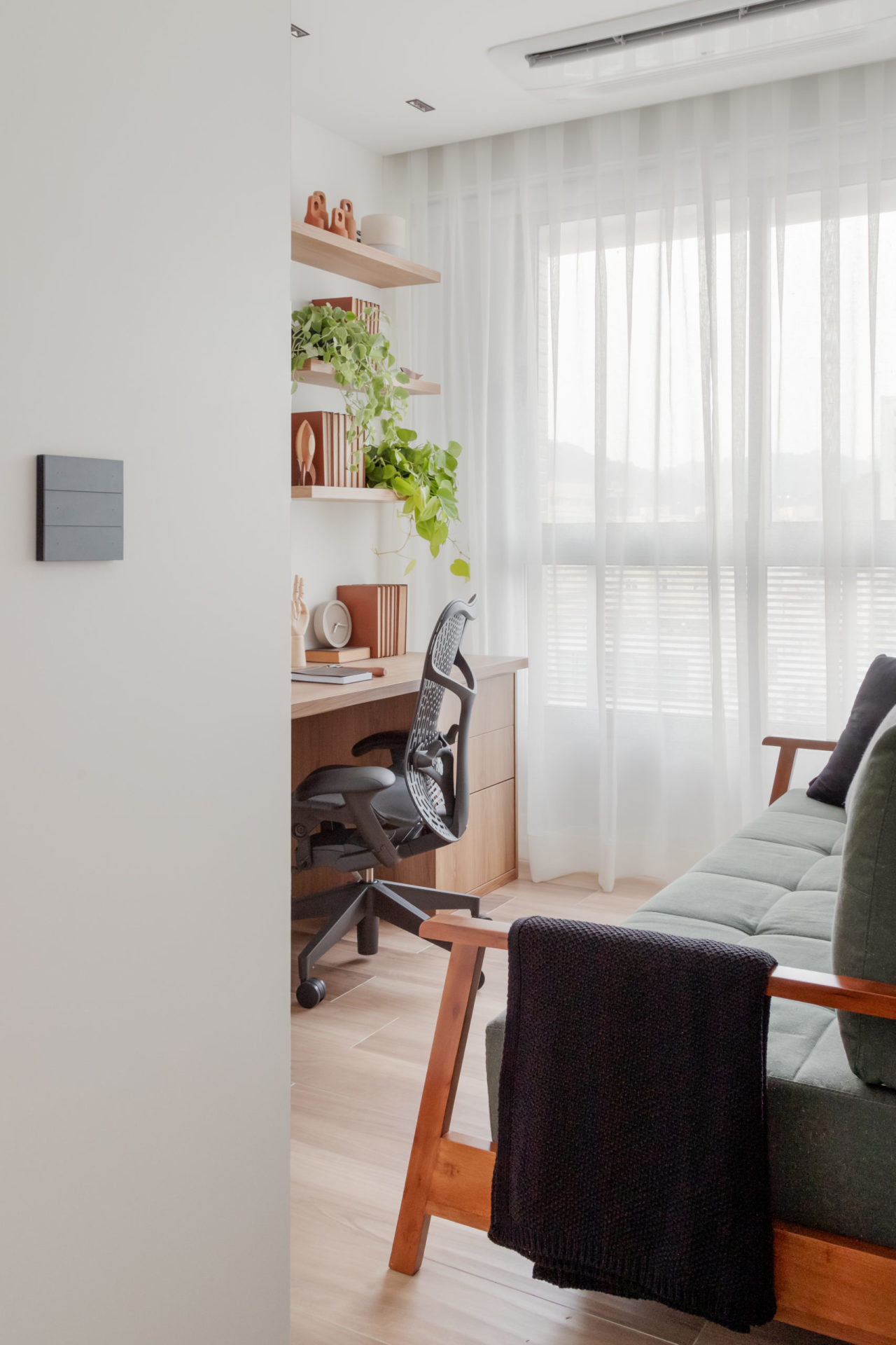 na foto escritório com sofá cinza, cadeira e mesa