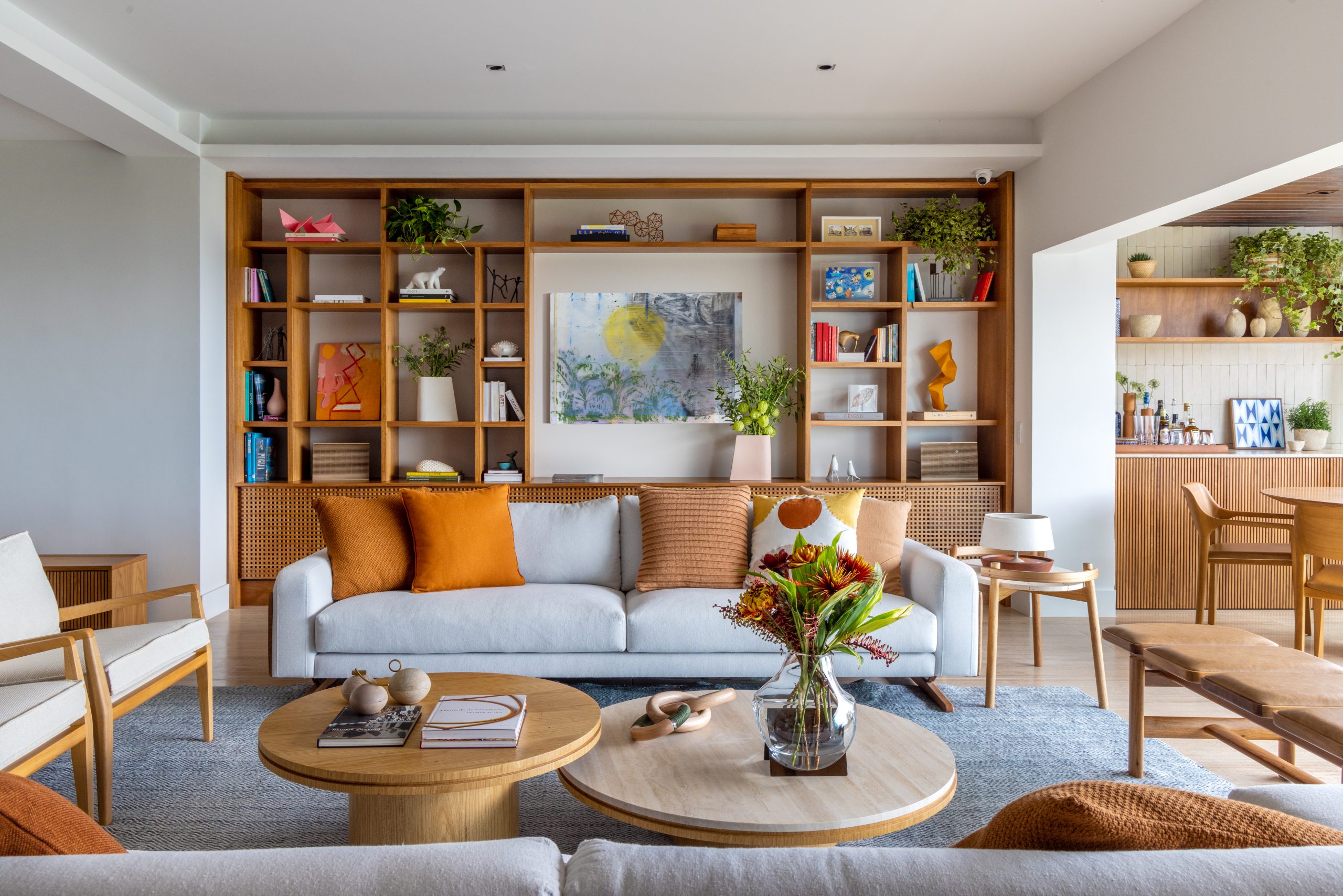 na foto sala de estar com estante na parede, sofá branco e varanda