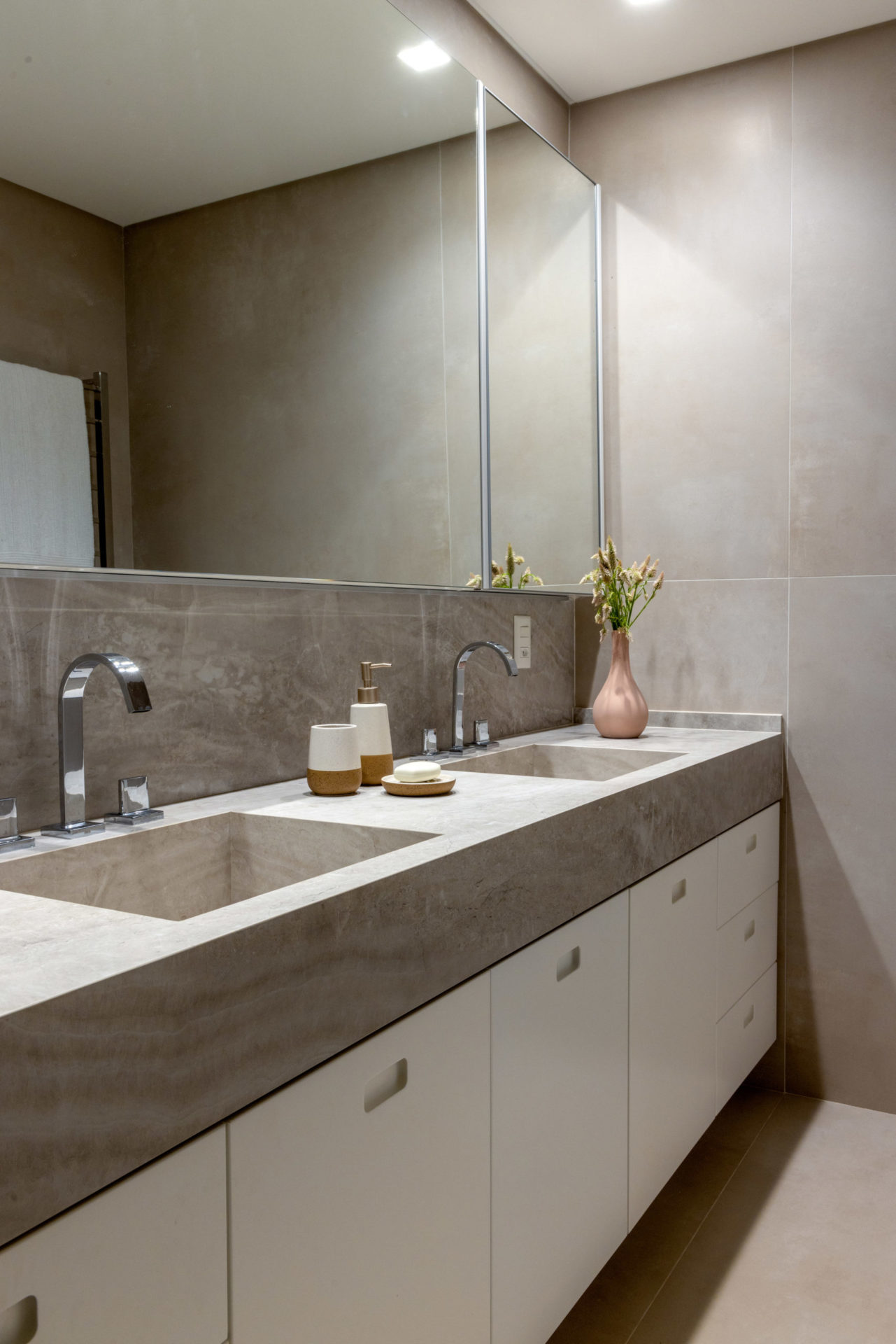 na foto banheiro de suíte com bancada branca e cinza cm duas pias e espelho grande