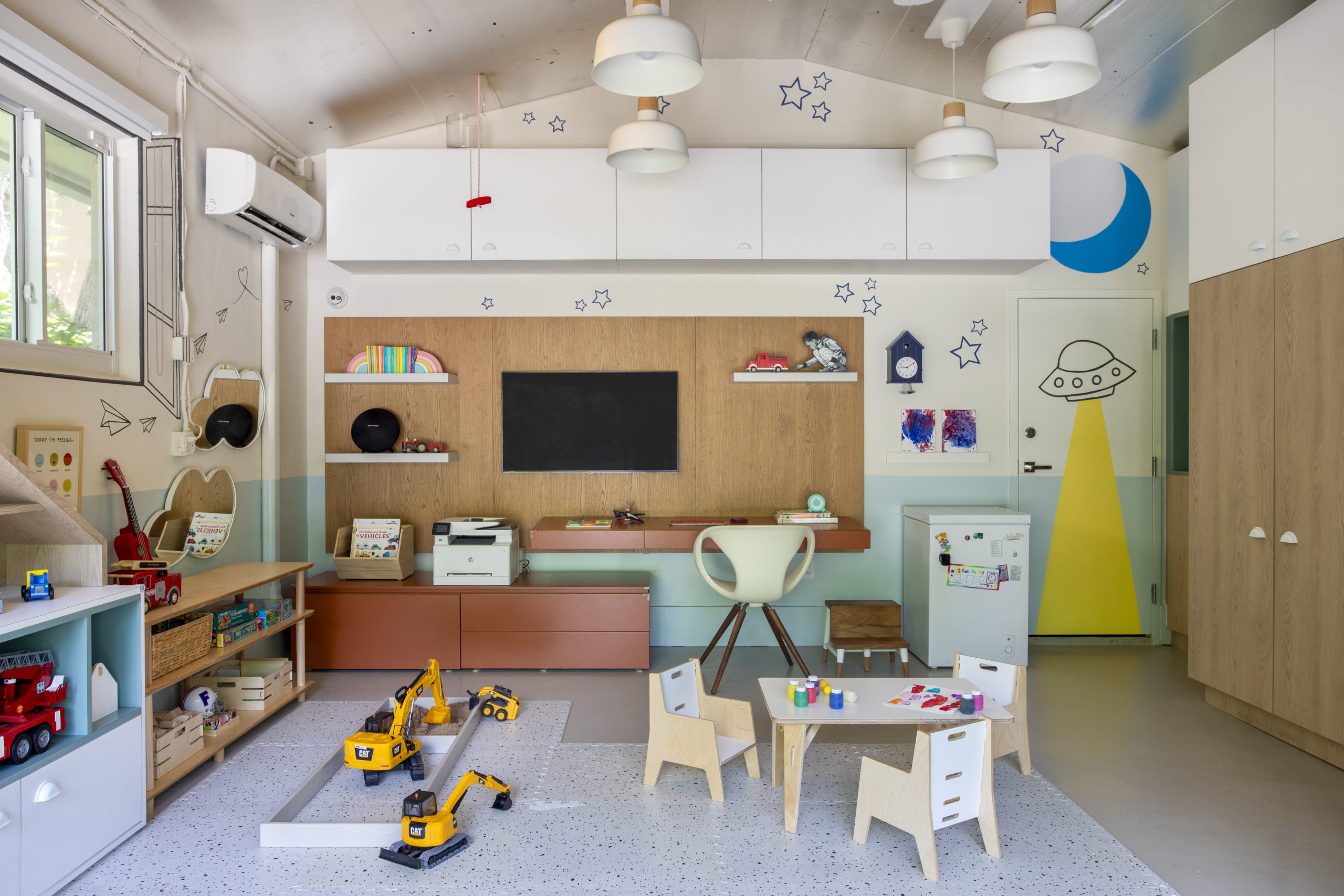 na foto uma brinquedoteca com brinquedos, instrumentos musicais e uma mesa de trabalho