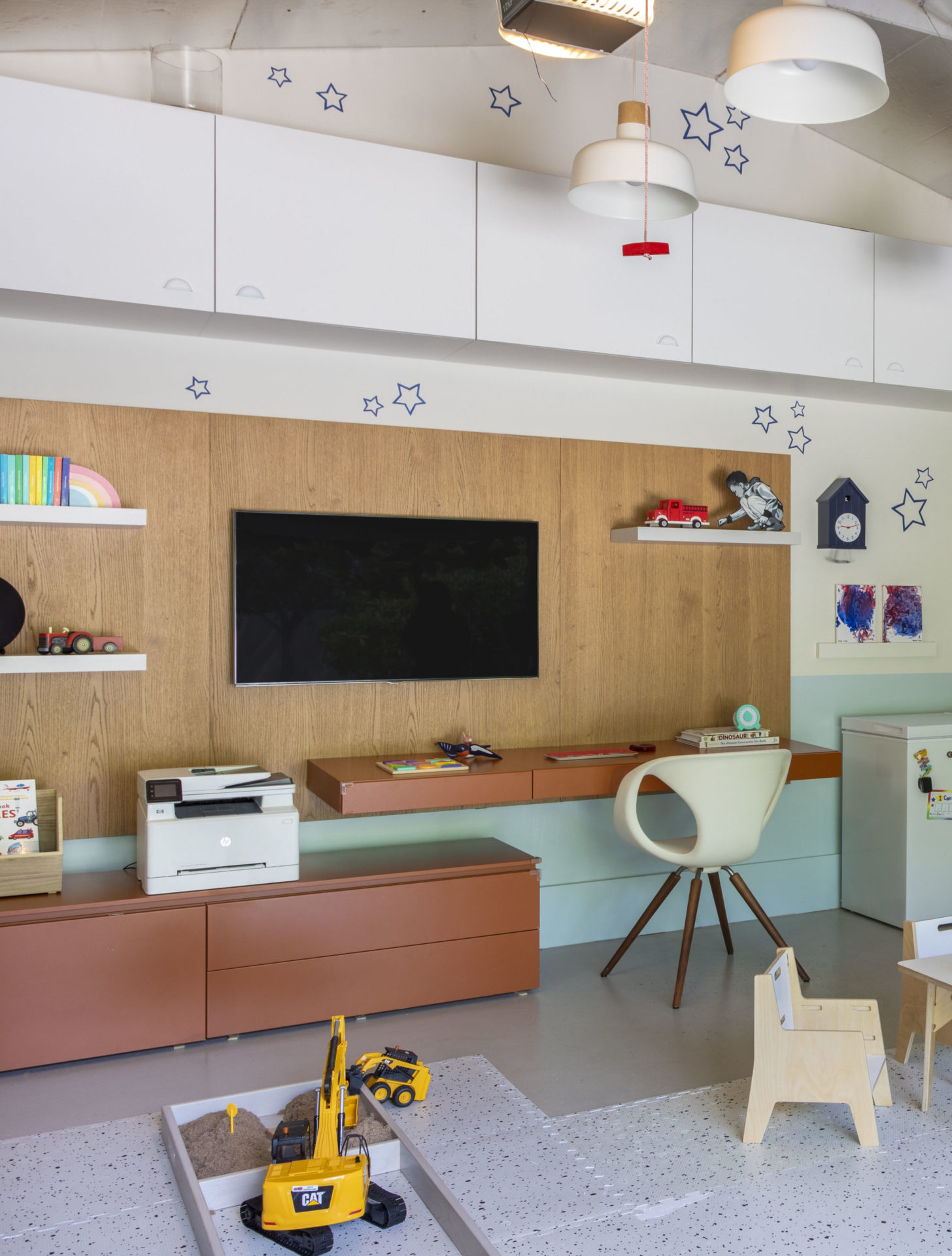 na foto um home office com uma TV na parede