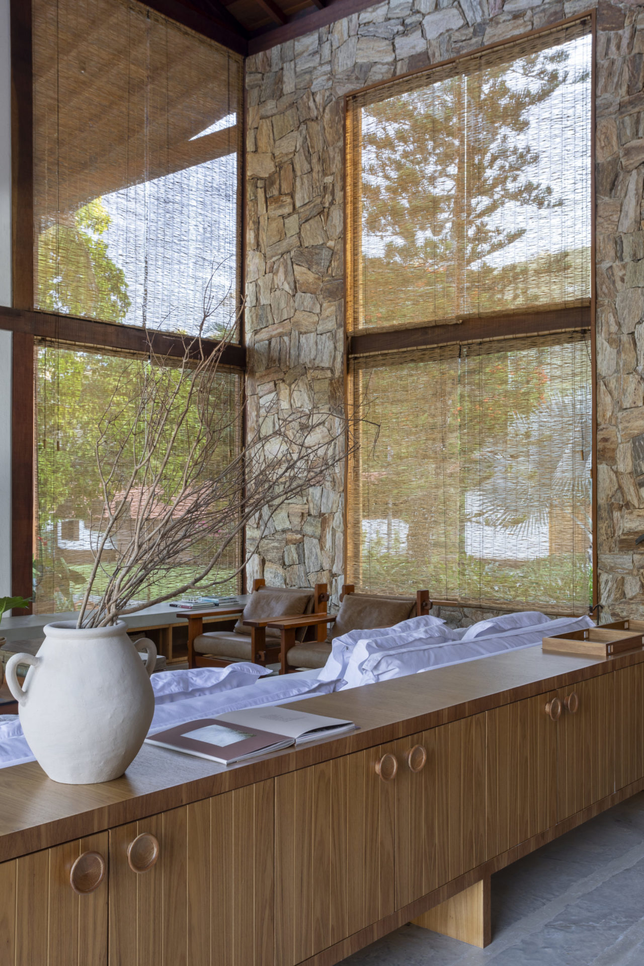 na foto sala com tons neutros e parede com pedras