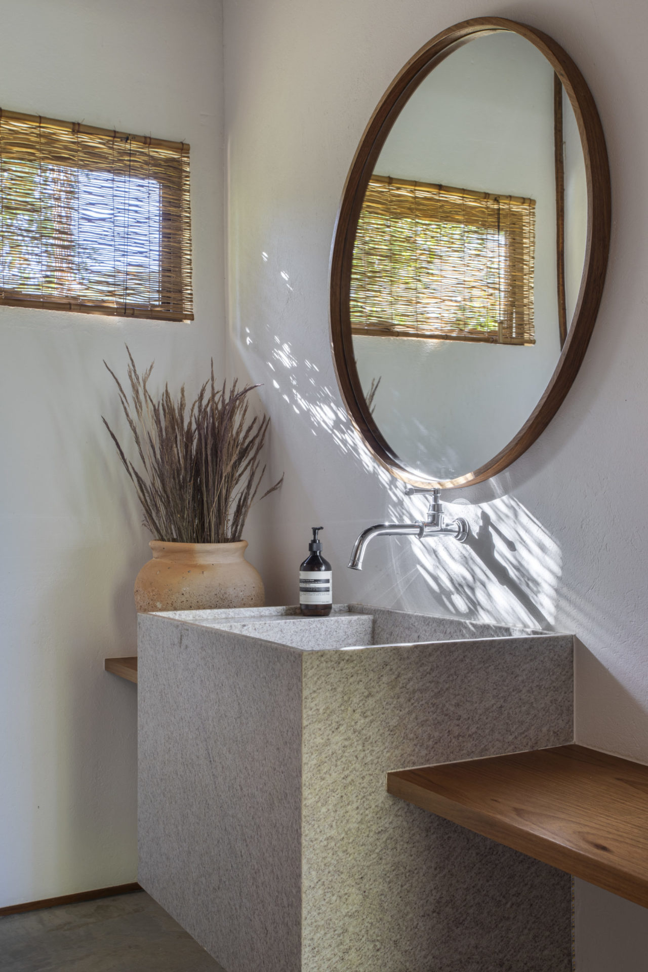 na foto lavabo com espelho redondo, pia e janela