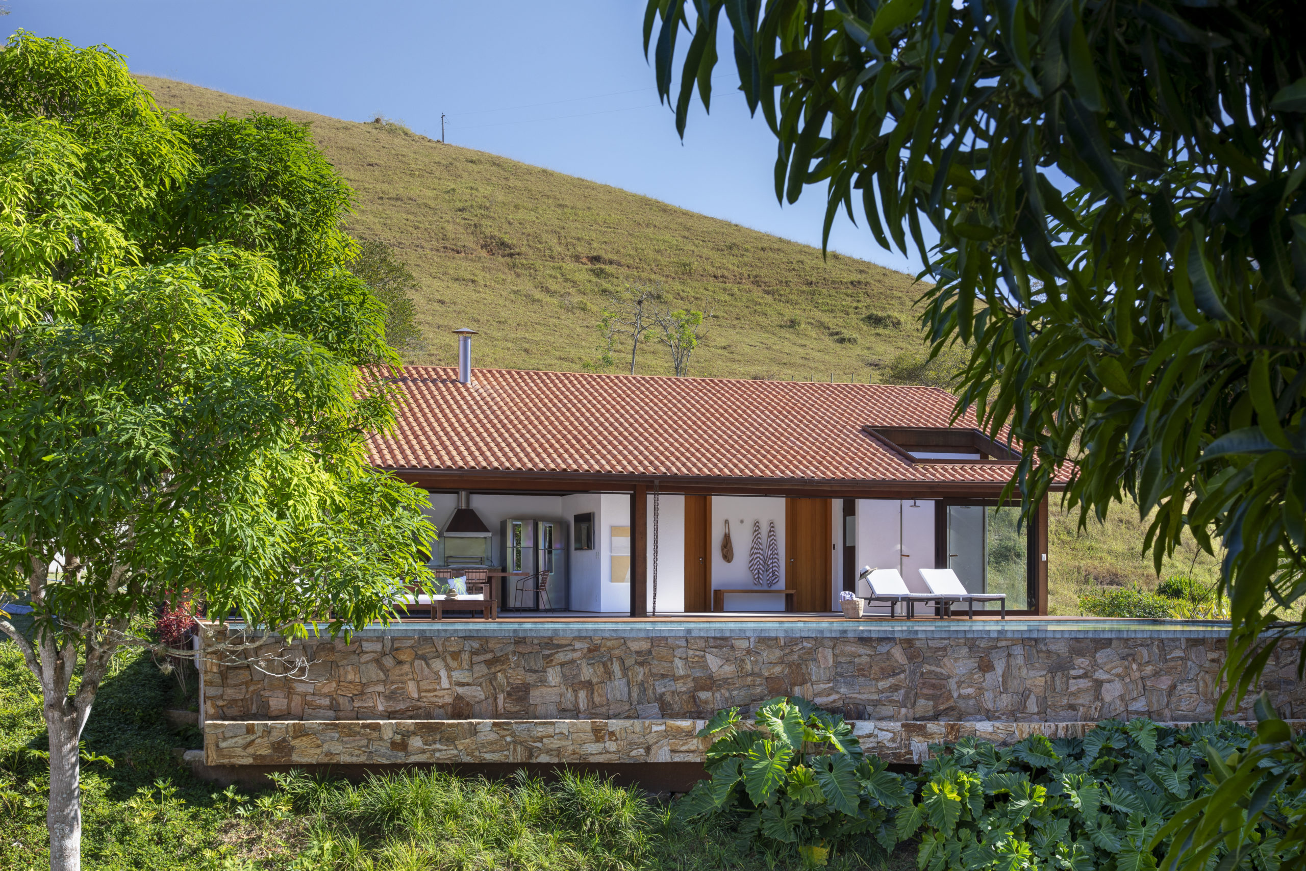 na foto vista de uma casa com piscina, churrasqueira e muito verde