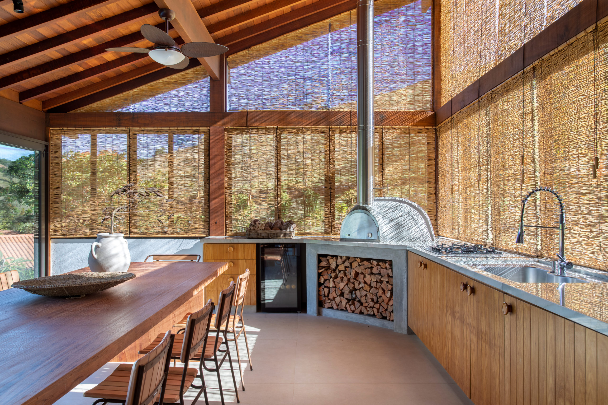 na foto parte interna de casa com forno a lenha e mesa para 12 pessoas