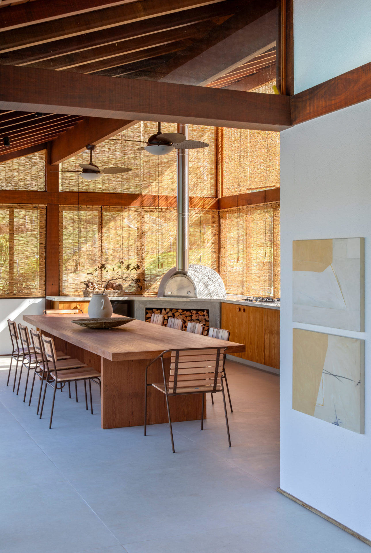 na foto casa com forno a lenha e mesa para 10 pessoas com ventiladores de teto