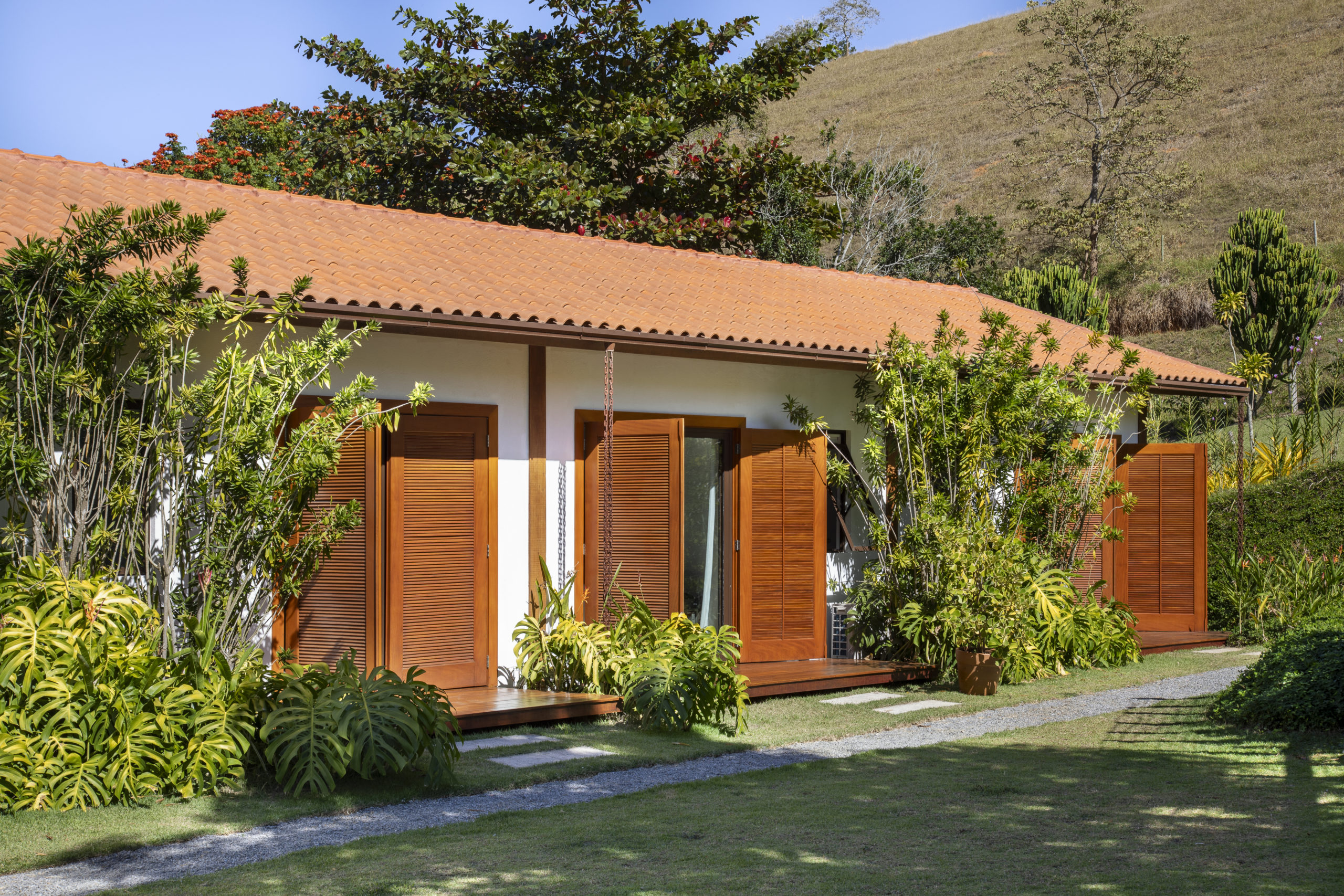na foto casa com portas de madeira abertas e muito verde