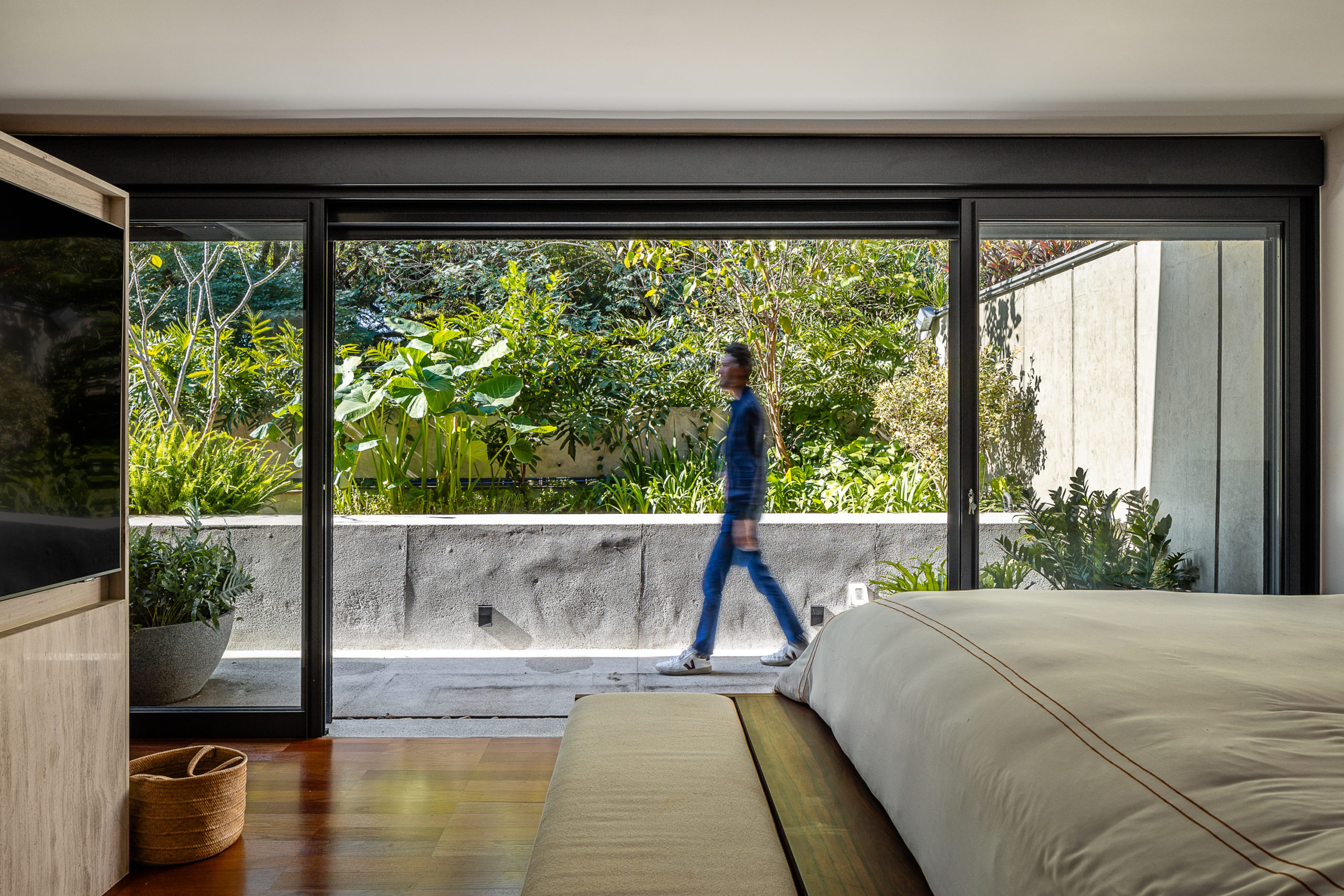 na foto sala de TV e um homem passando na varanda