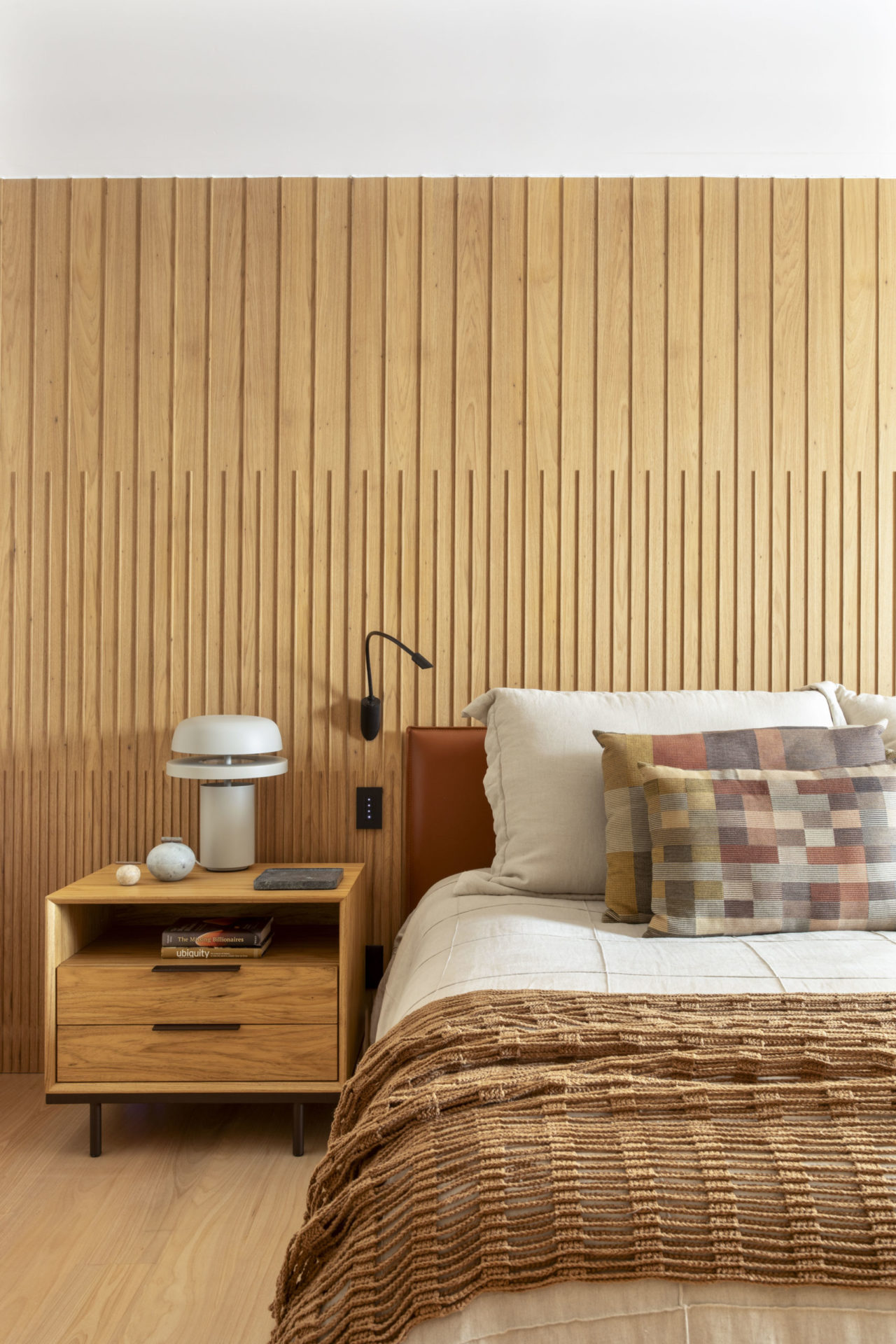 na foto cama de casal, mesinha de cabeceira e parede em madeira