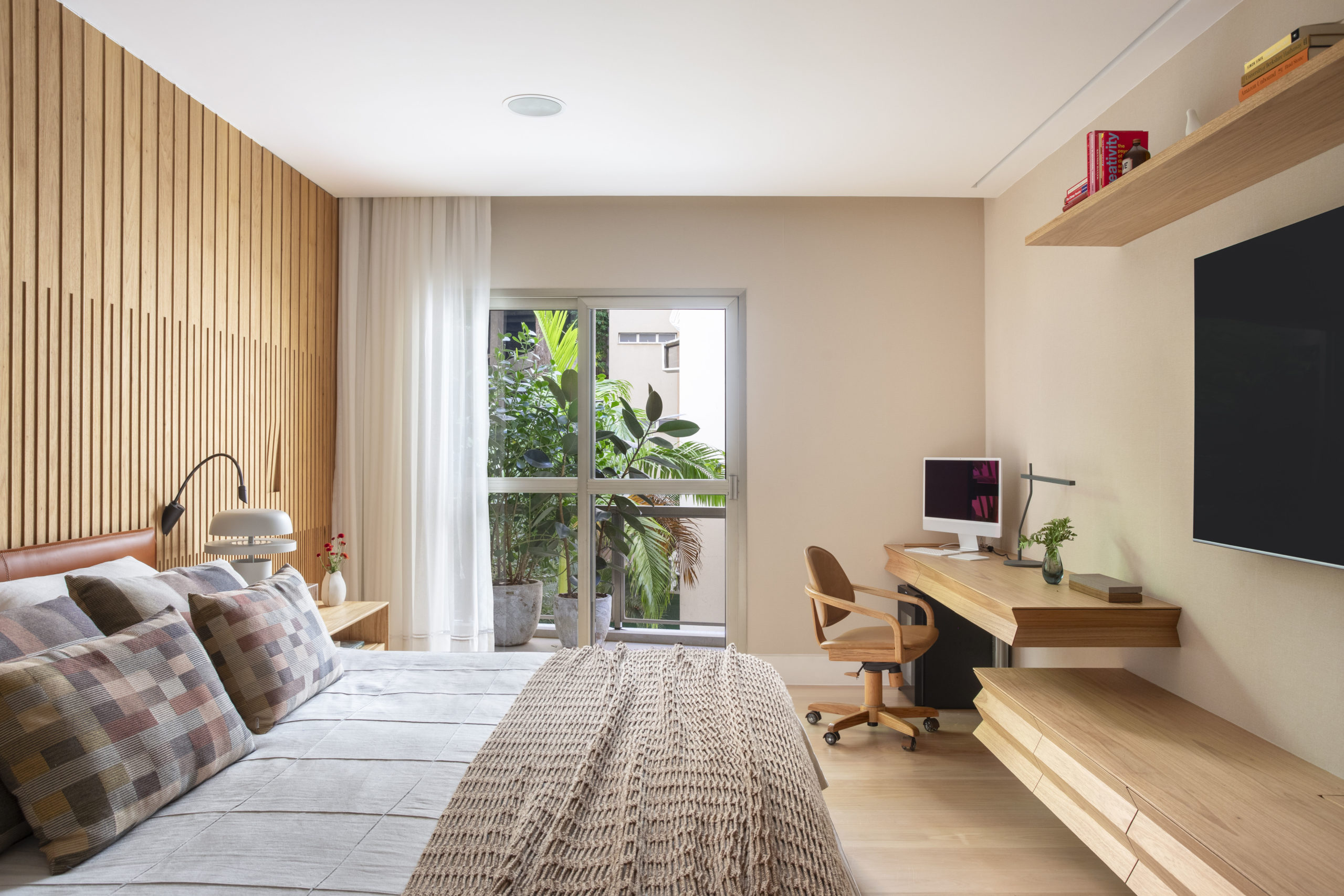 na foto quarto de casal com cama, rack, TV e varanda