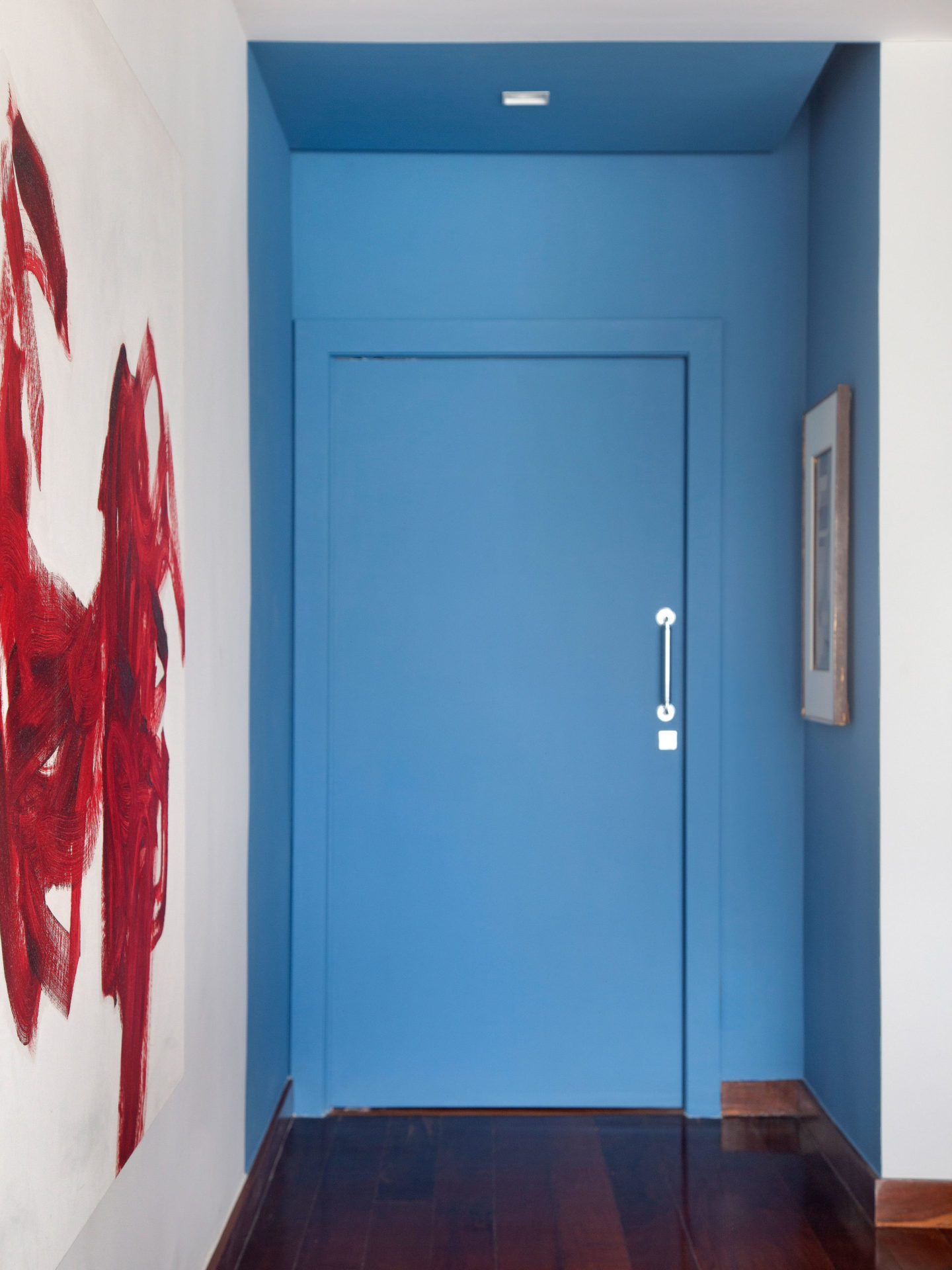 na foto uma porta na cor azul e um quadro na parede