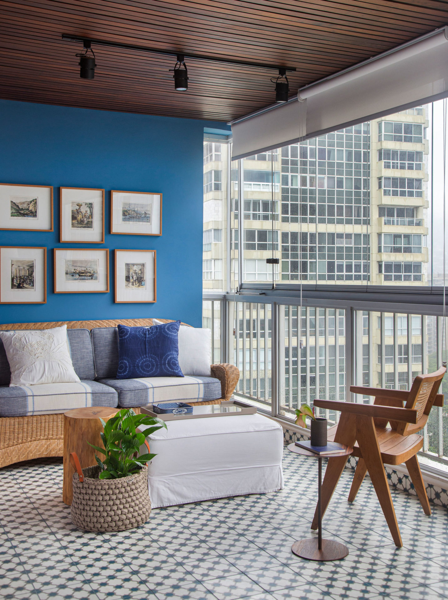 varanda com parede azul com seis quadros, um sofá