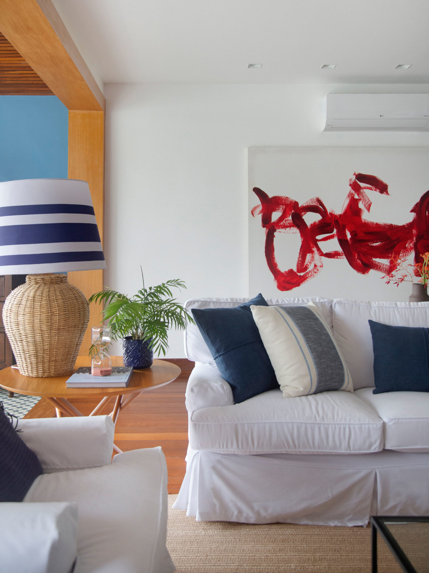 na foto sala com piso de madeira sofá branco e quadro na parede