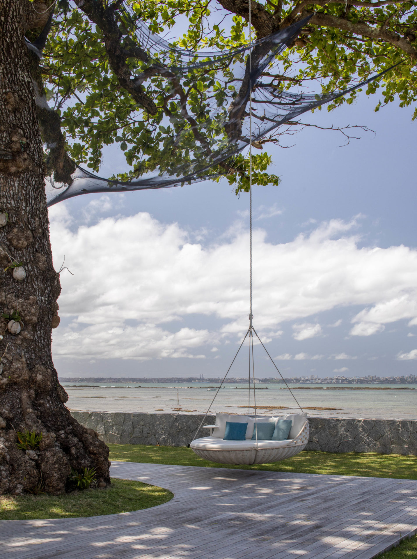 na foto área externa de casa de praia com um balanço preso a uma árvore