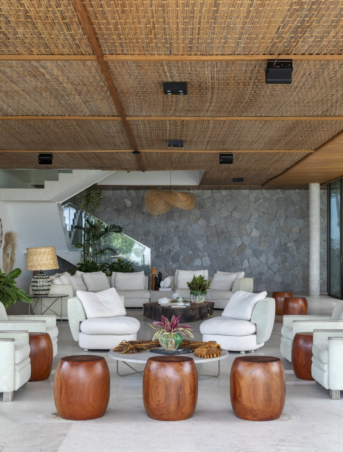 na foto sala com sofá, banquetas e escada para o segundo piso