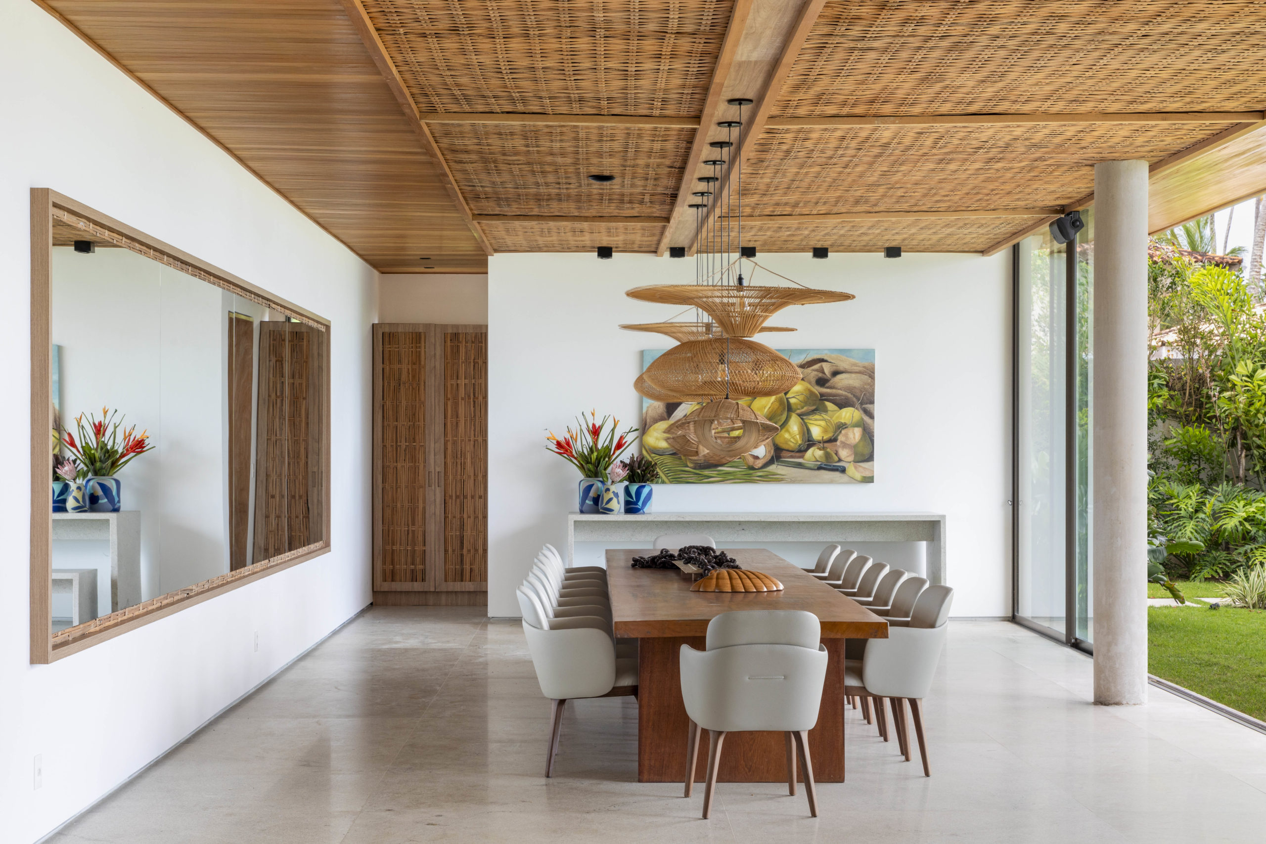 na foto sala de jantar com mesa de jantar grande, espelho e quadro na parede 