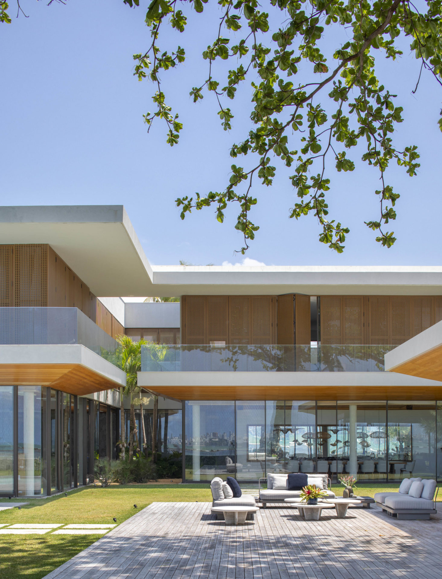 na foto casa de dois andares, com espreguiçadeiras e paredes de vidro