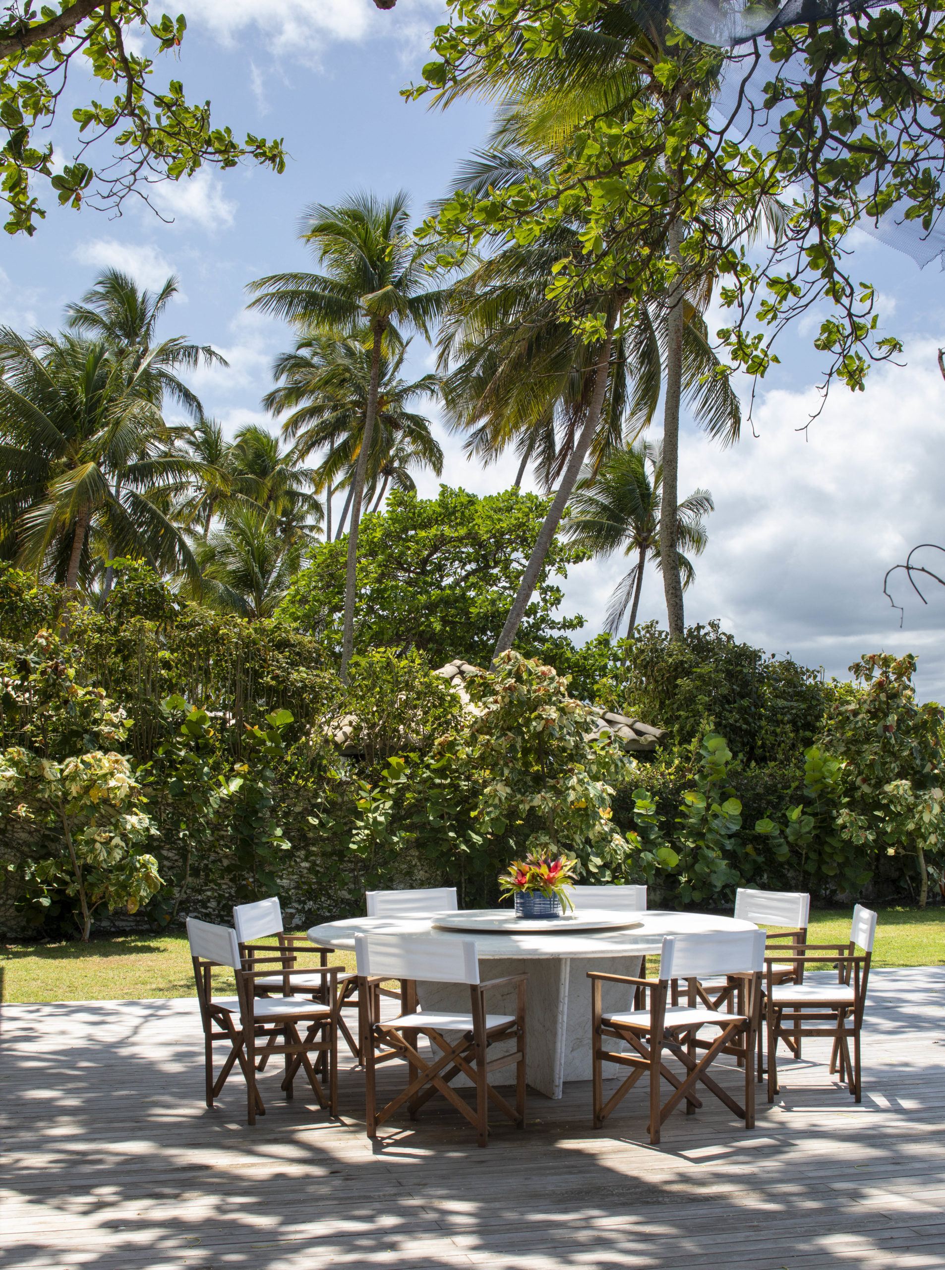 na foto área externa de casa de praia com mesa e cadeiras brancas