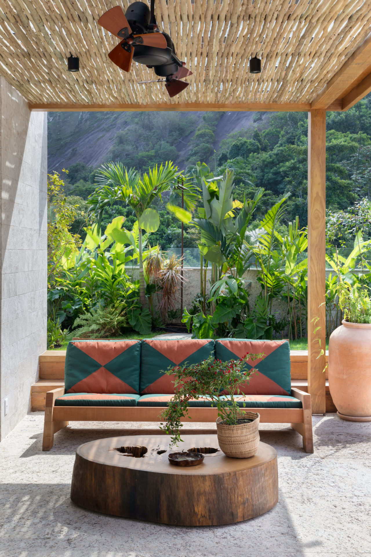 na foto segundo andar de cobertura duplex com sofá colorido, mesa de madeira e plantas
