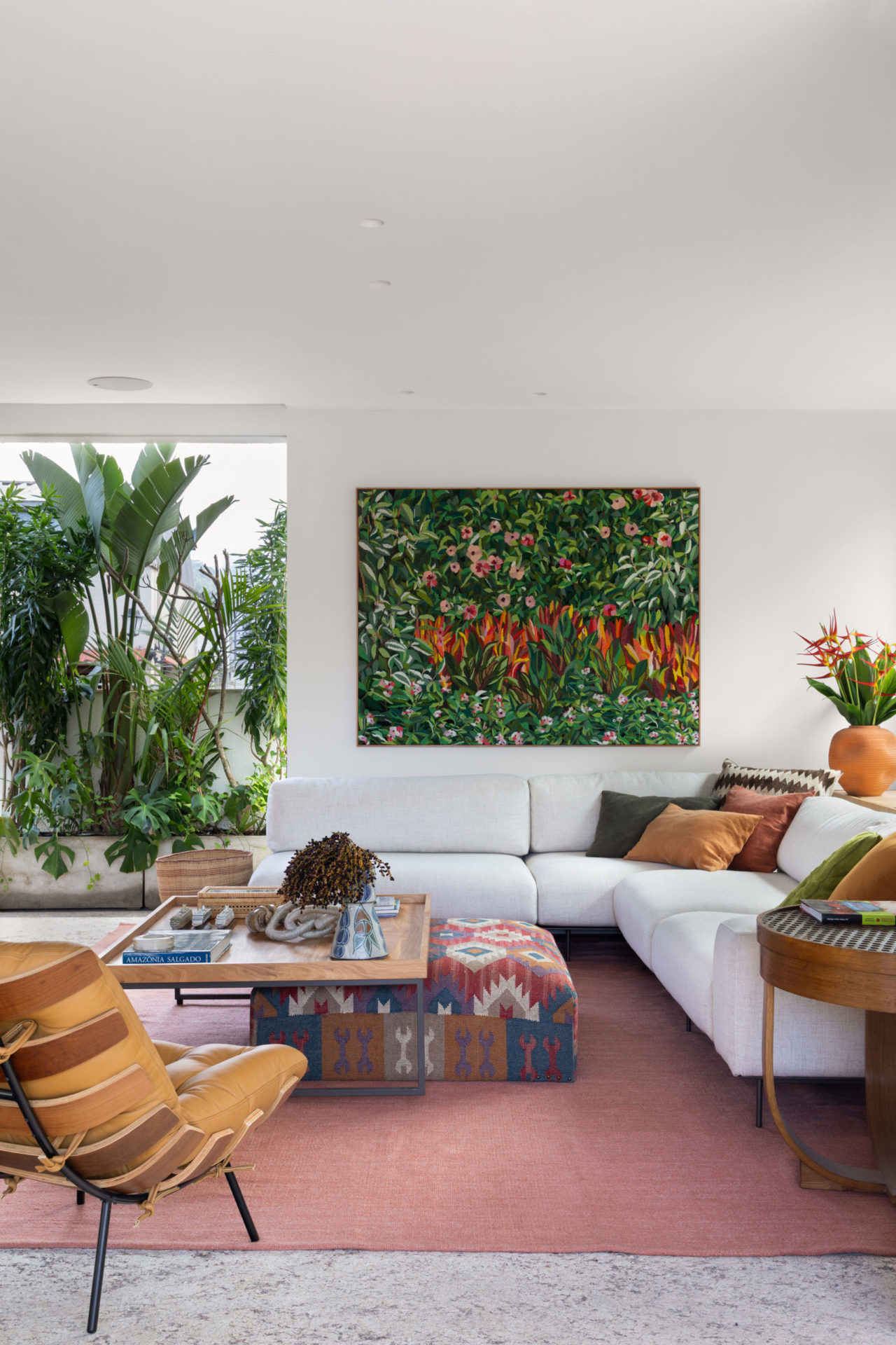 sala com sofá branco e quadro da artista Mucki Botkay, que traz vegetação bordada