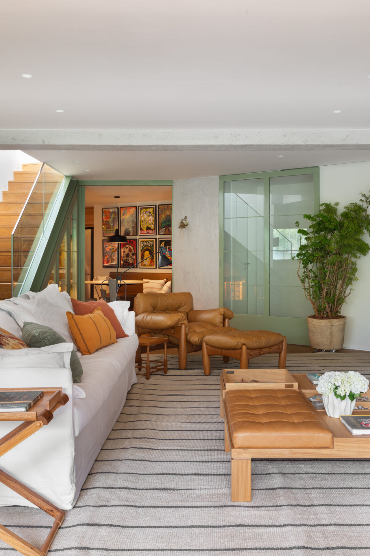 sala com mesa de centro em madeira e couro, sofá branco, escada e poltrona mole em couro