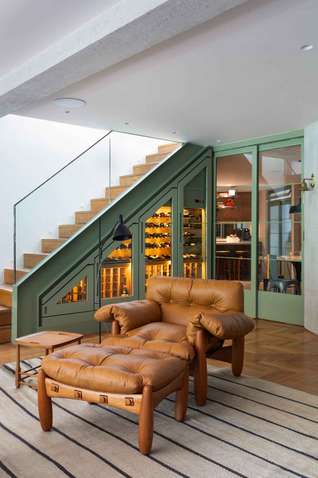 na foto poltrona mole de couro em uma sala com escada e luminária de pé