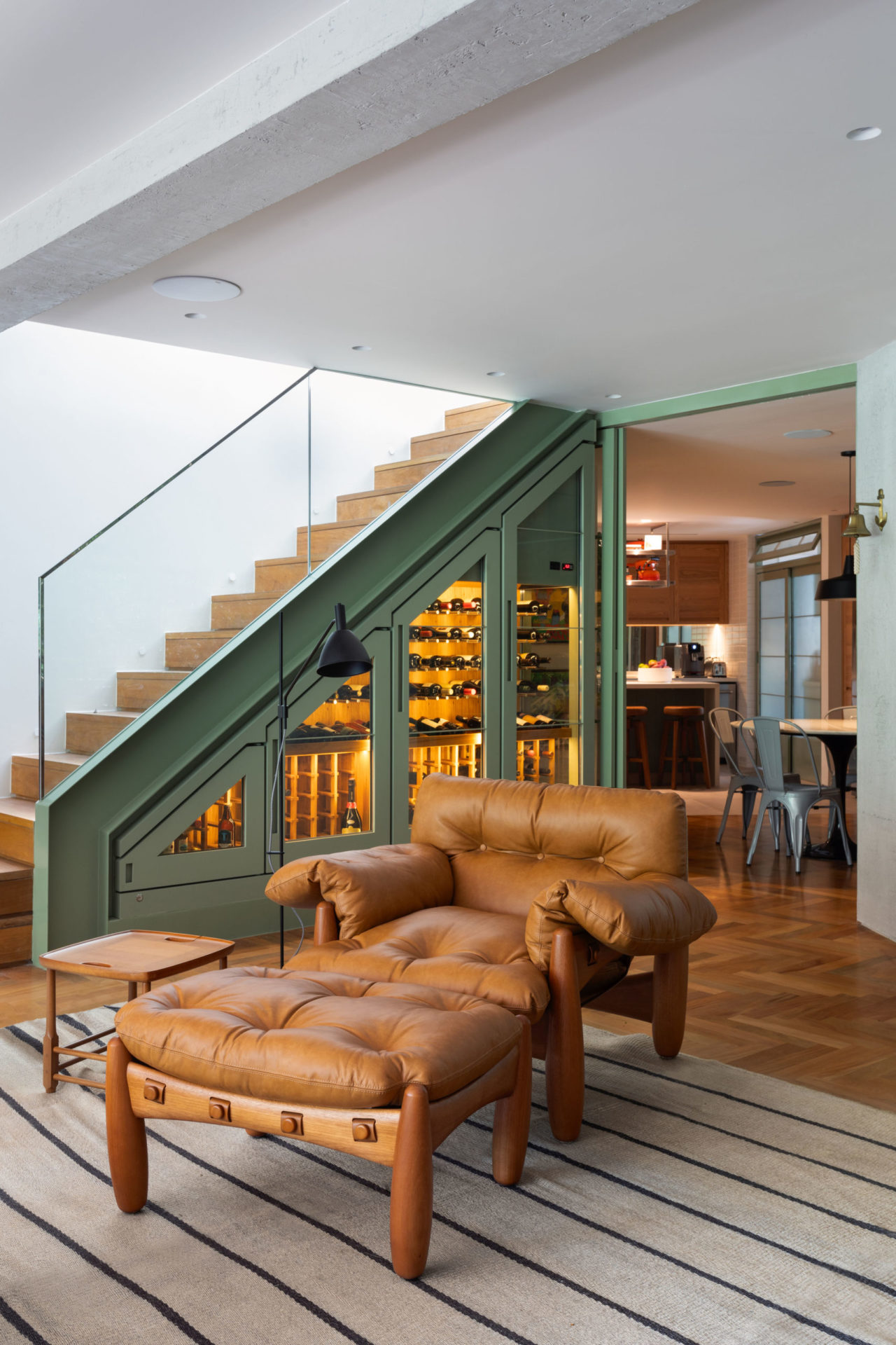 na foto sala com piso em taco , escada e poltrona de couro