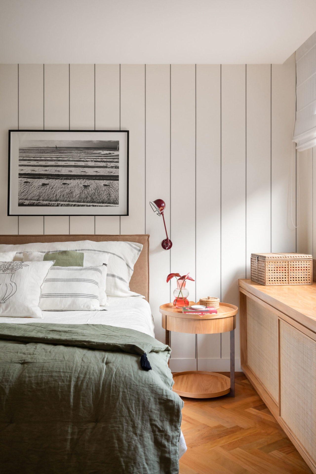 na foto quarto com cama de casal, quadro na parede ripada branca e cômoda