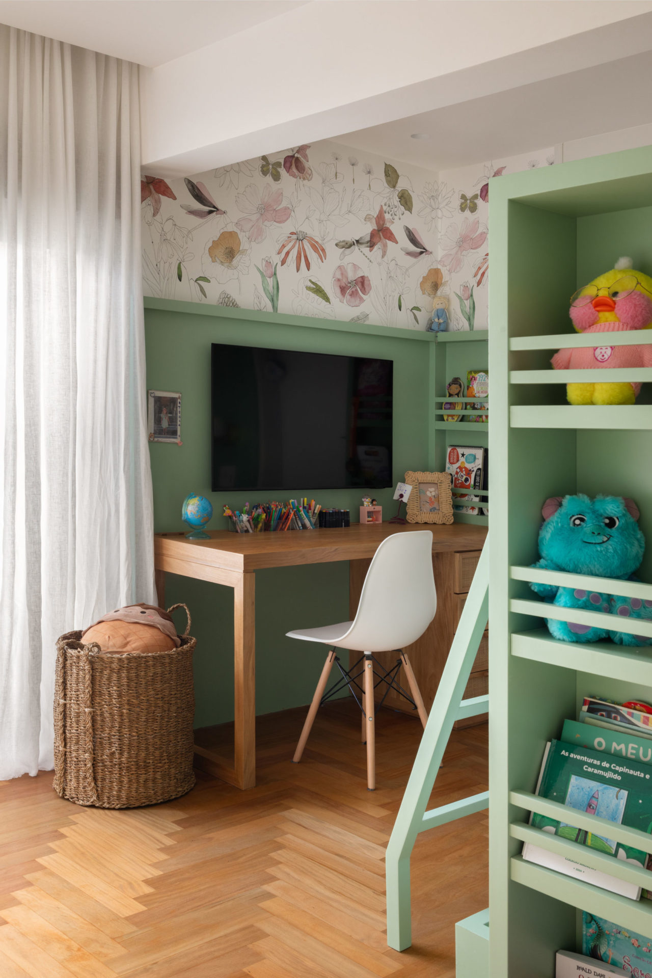 na foto quarto infantil de menina com estantes verde claras, mesinha com cadeira e tv