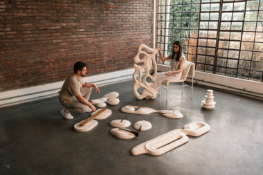 na foto uma mulher branca de cabelos compridos, um homem branco, em uma sala com esculturas