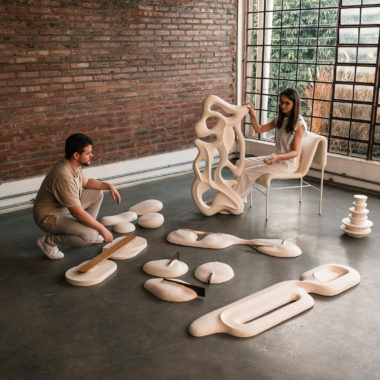 na foto uma mulher branca de cabelos compridos, um homem branco, em uma sala com esculturas
