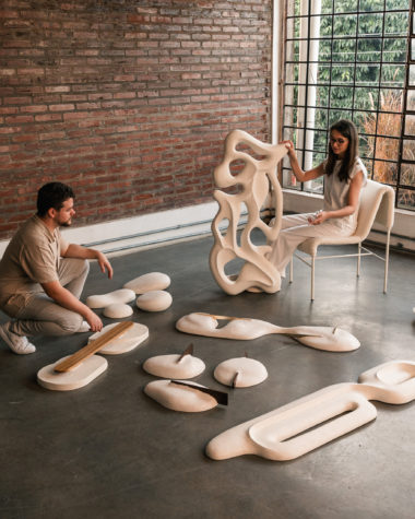 na foto uma mulher branca de cabelos compridos, um homem branco, em uma sala com esculturas