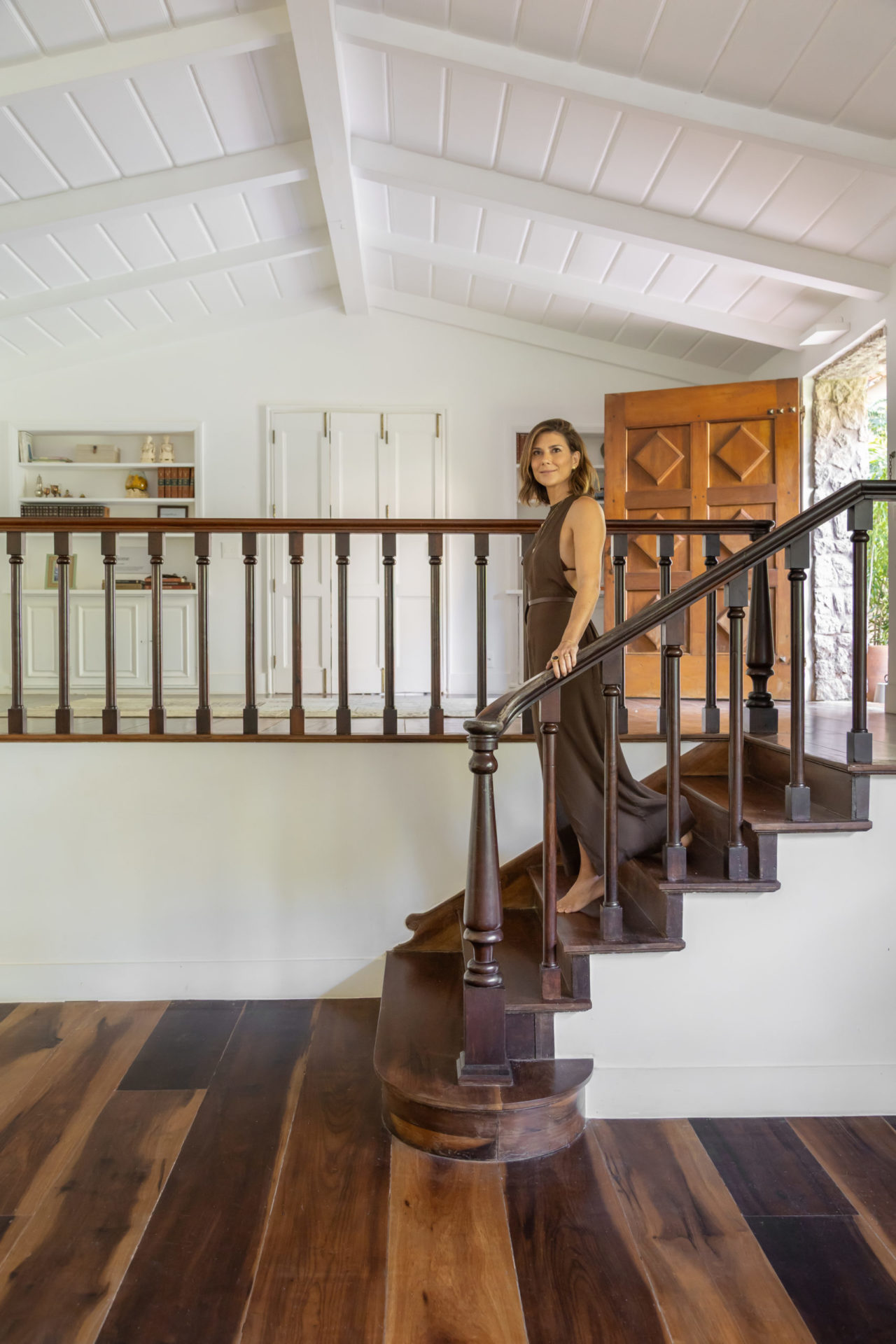 na foto mulher alta, magra, branca de cabelos curtos desce escada de madeira em casa dos anos 1940