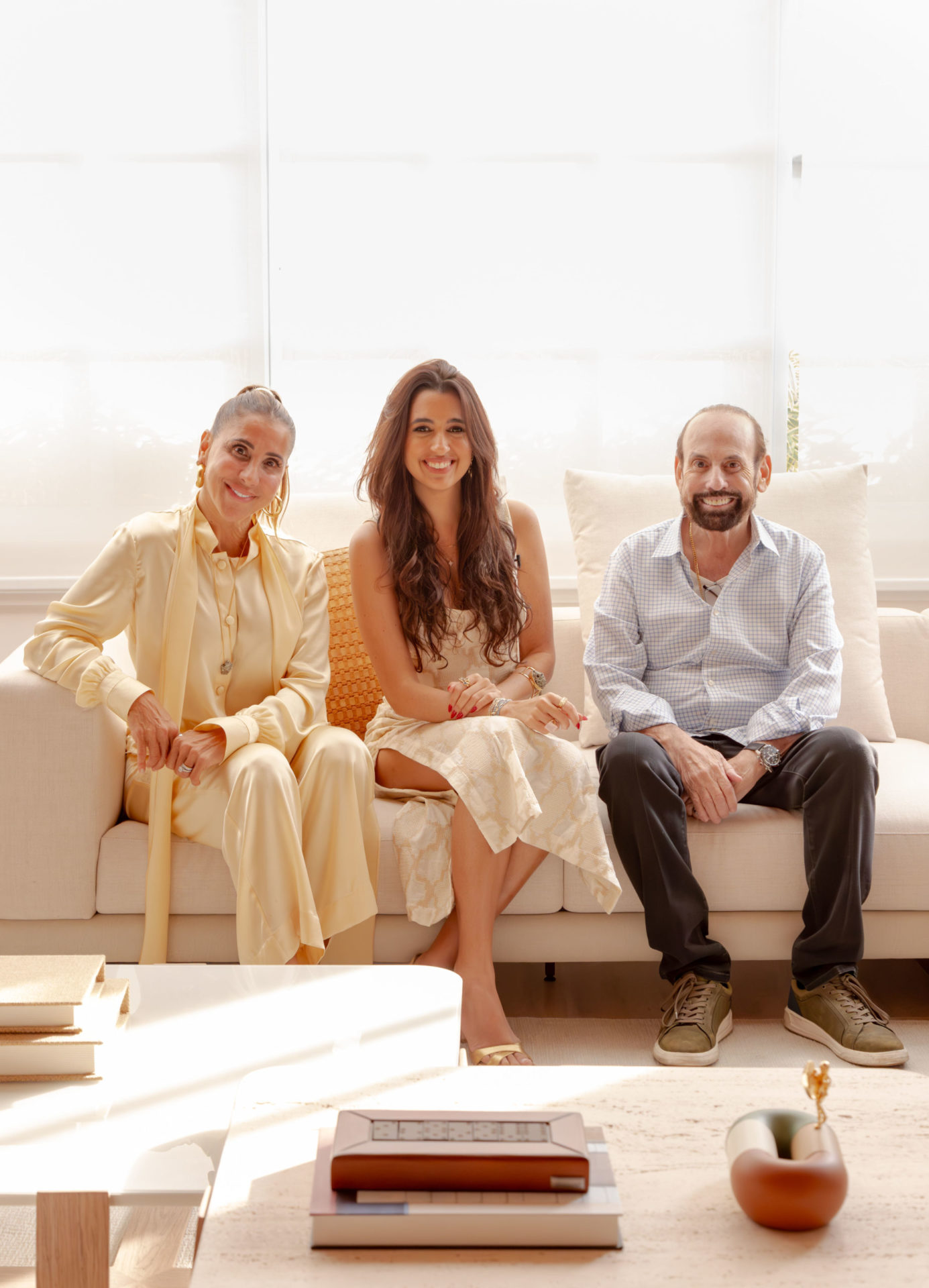 na foto duas mulheres e um homem sentado em um sofá branco