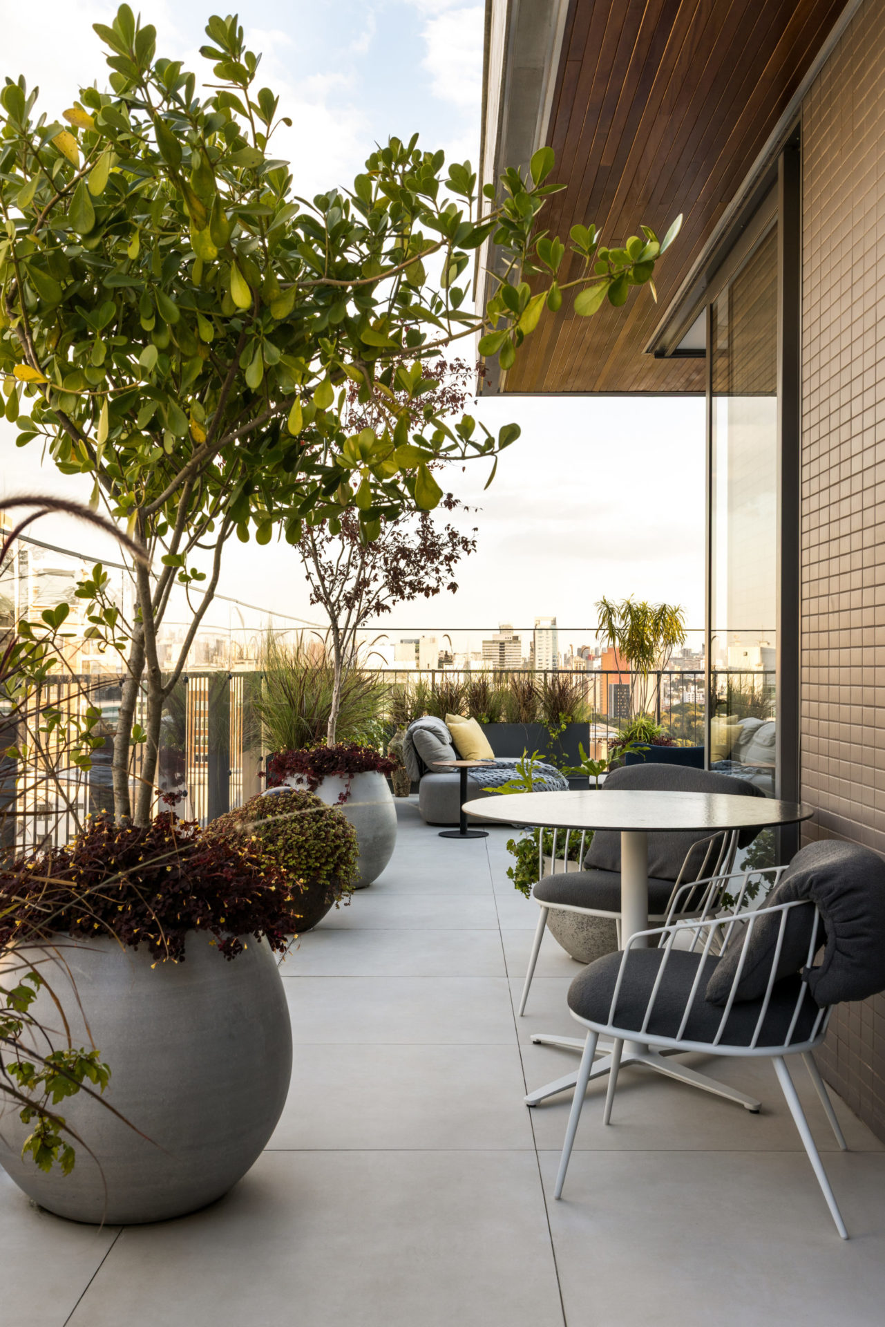 na foto varanda com mesinha, cadeira, sofás e plantas em vasos grandes